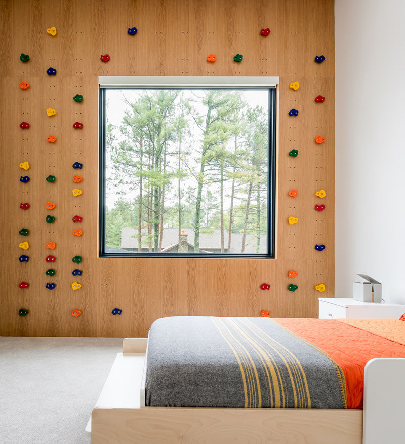 В этой современной детской спальне стена для скалолазания окружает окно, а небольшие наборы отверстий в деревянной стене позволяют перемещать «камни», чтобы создать новую задачу для лазания, когда это необходимо. #RockClimbingWall #KidsBedroom #BedroomDesign