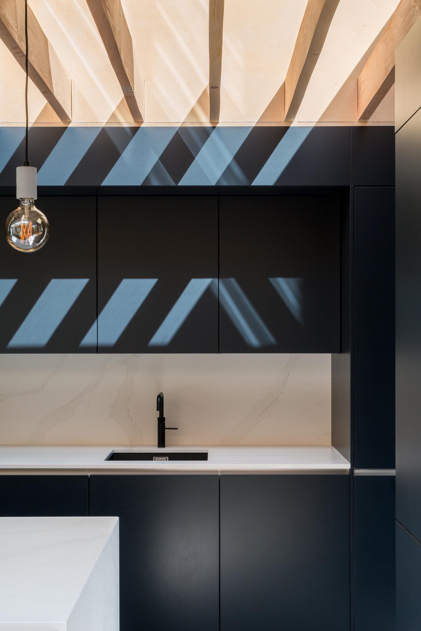 Современные матовые черные кухонные шкафы контрастируют с белыми столешницами.