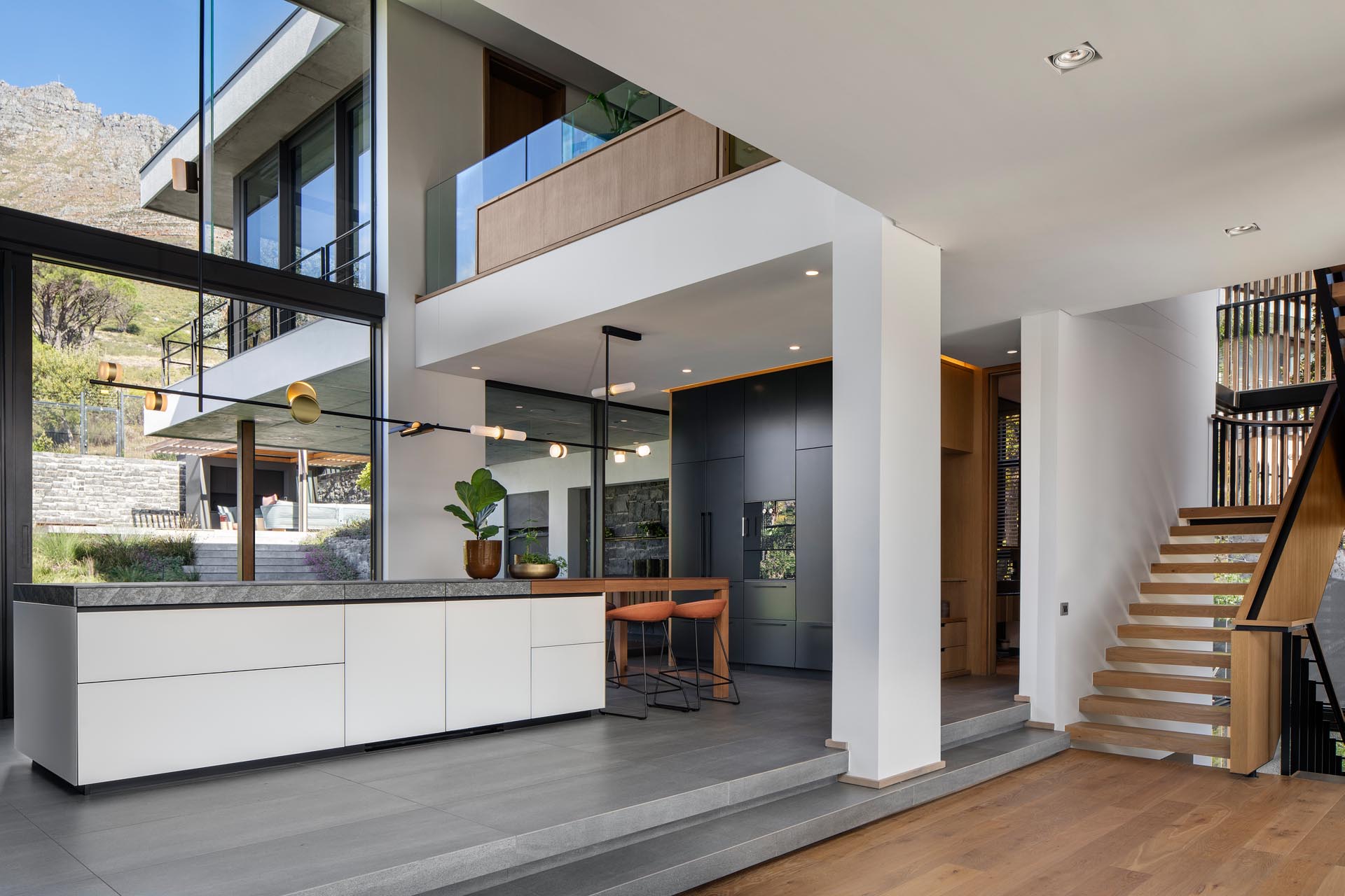 Современная кухня с минималистскими шкафами, высоким потолком и множеством окон.