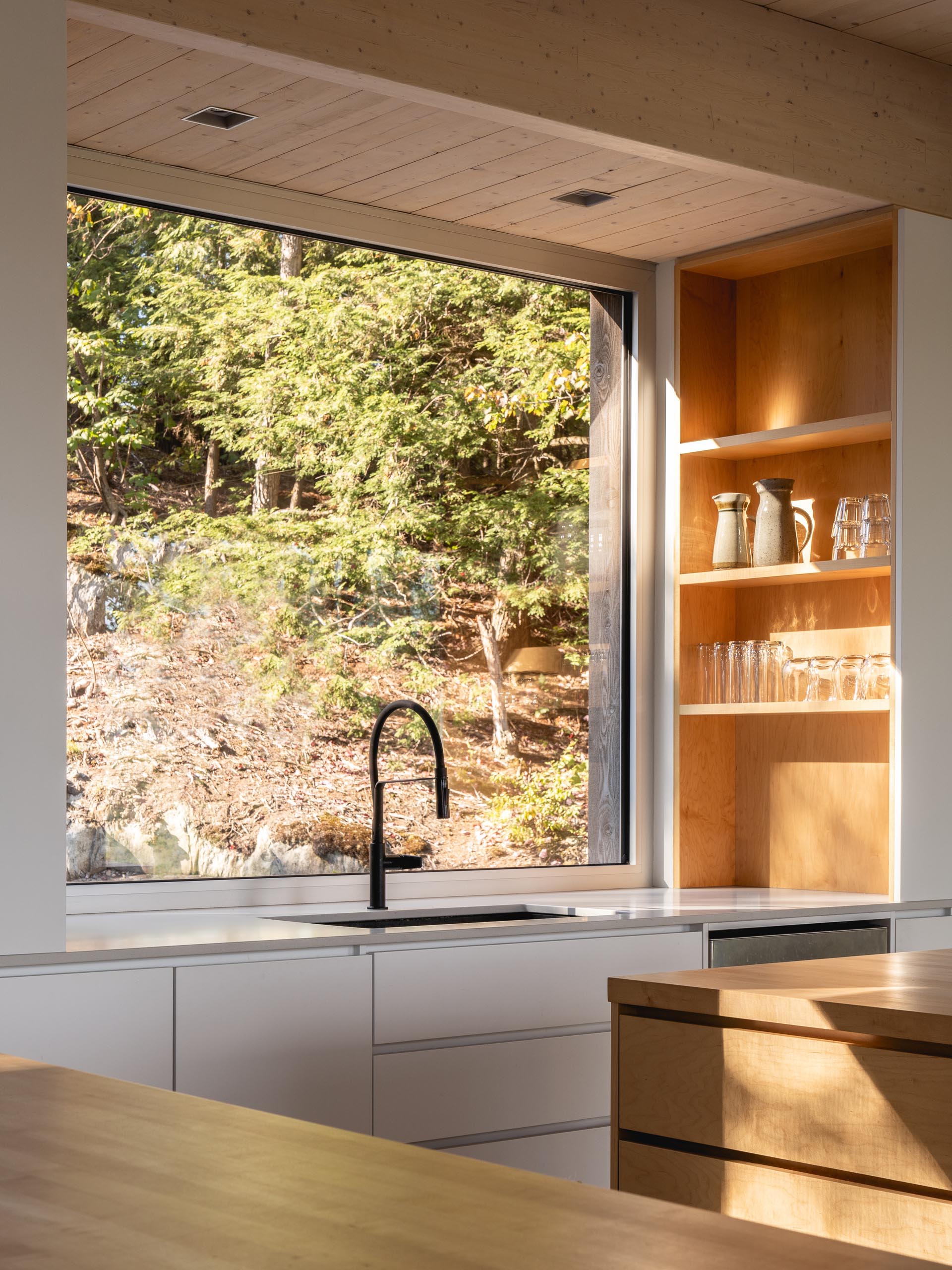 В этой современной кухне есть два кухонных острова из массива клена, полированный бетонный пол и большое квадратное окно над раковиной.