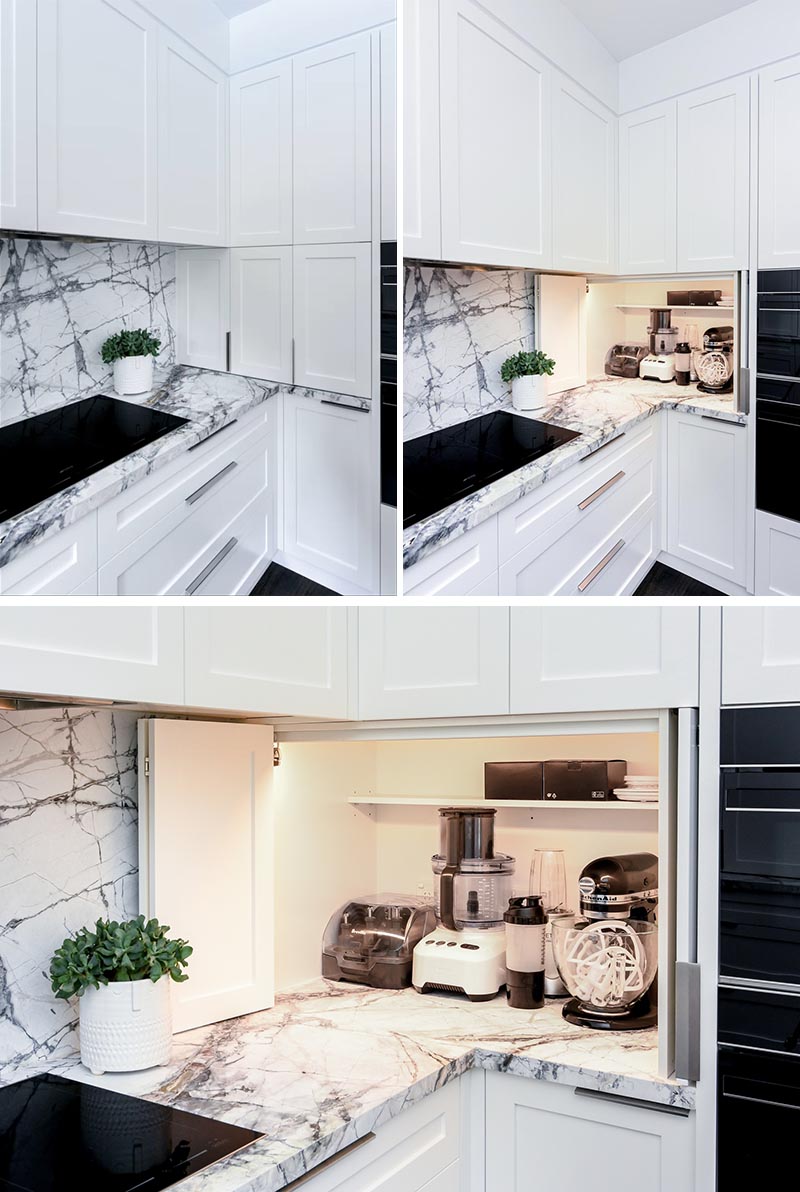 В углу этой современной серо-белой кухни находится гараж для бытовой техники, в котором хранятся блендеры и миксеры. Внутреннее освещение позволяет легко видеть предметы внутри шкафа. #KitchenDesign #KitchenIdeas #KitchenStorage #KitchenOrganization #ApplianceGarage