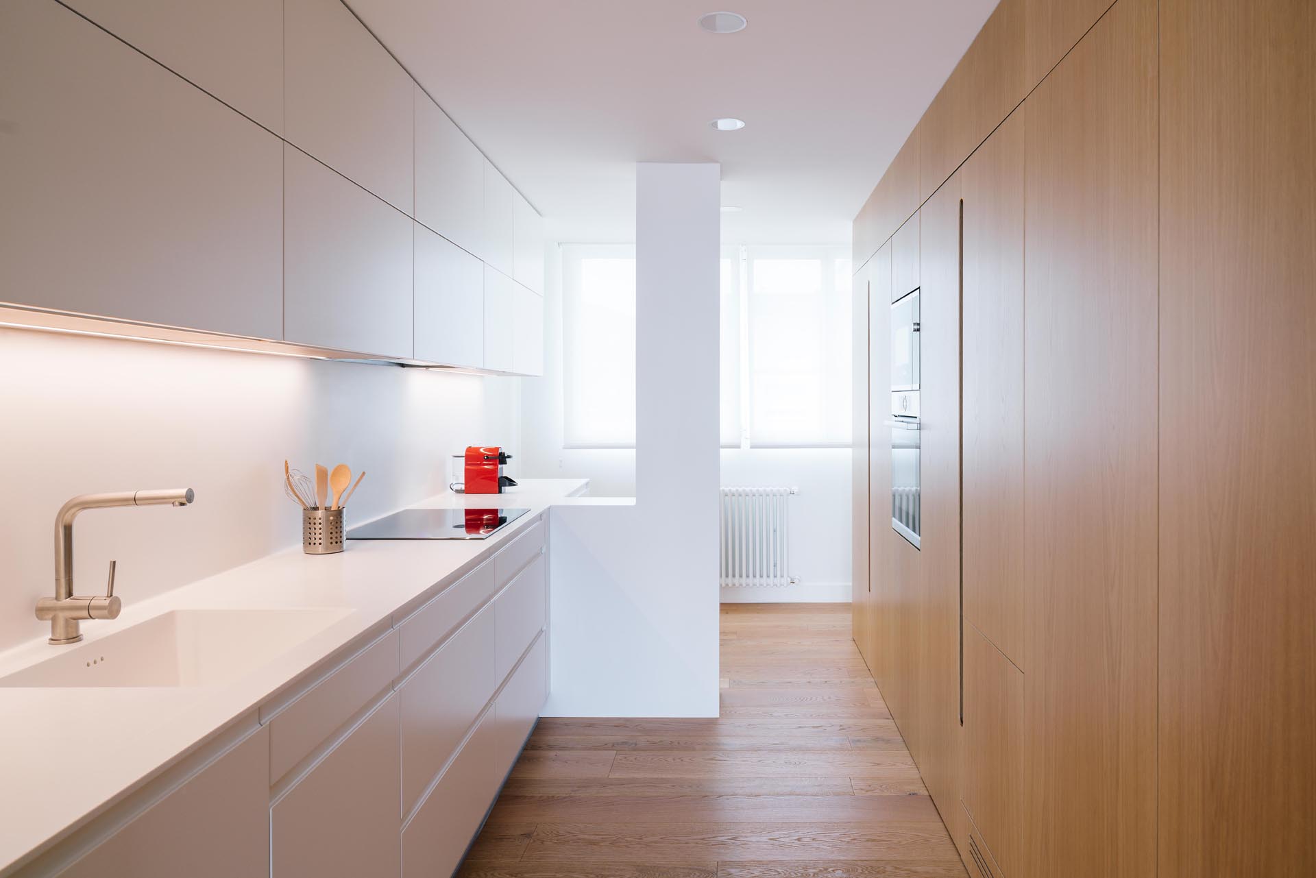 Современная кухня с минималистскими белыми и деревянными шкафами.