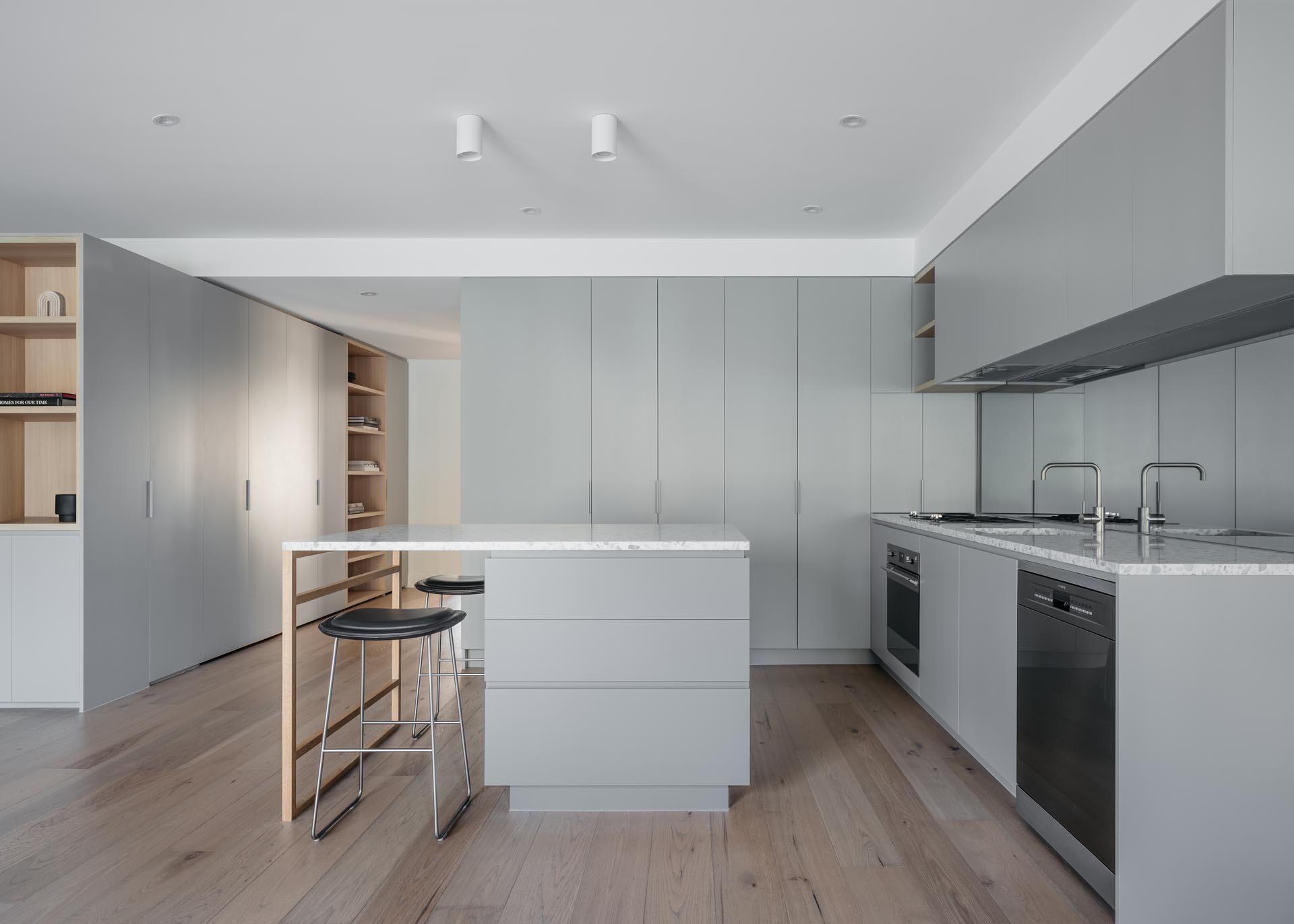 Современная кухня с минималистичными светло-серыми шкафами и островом.