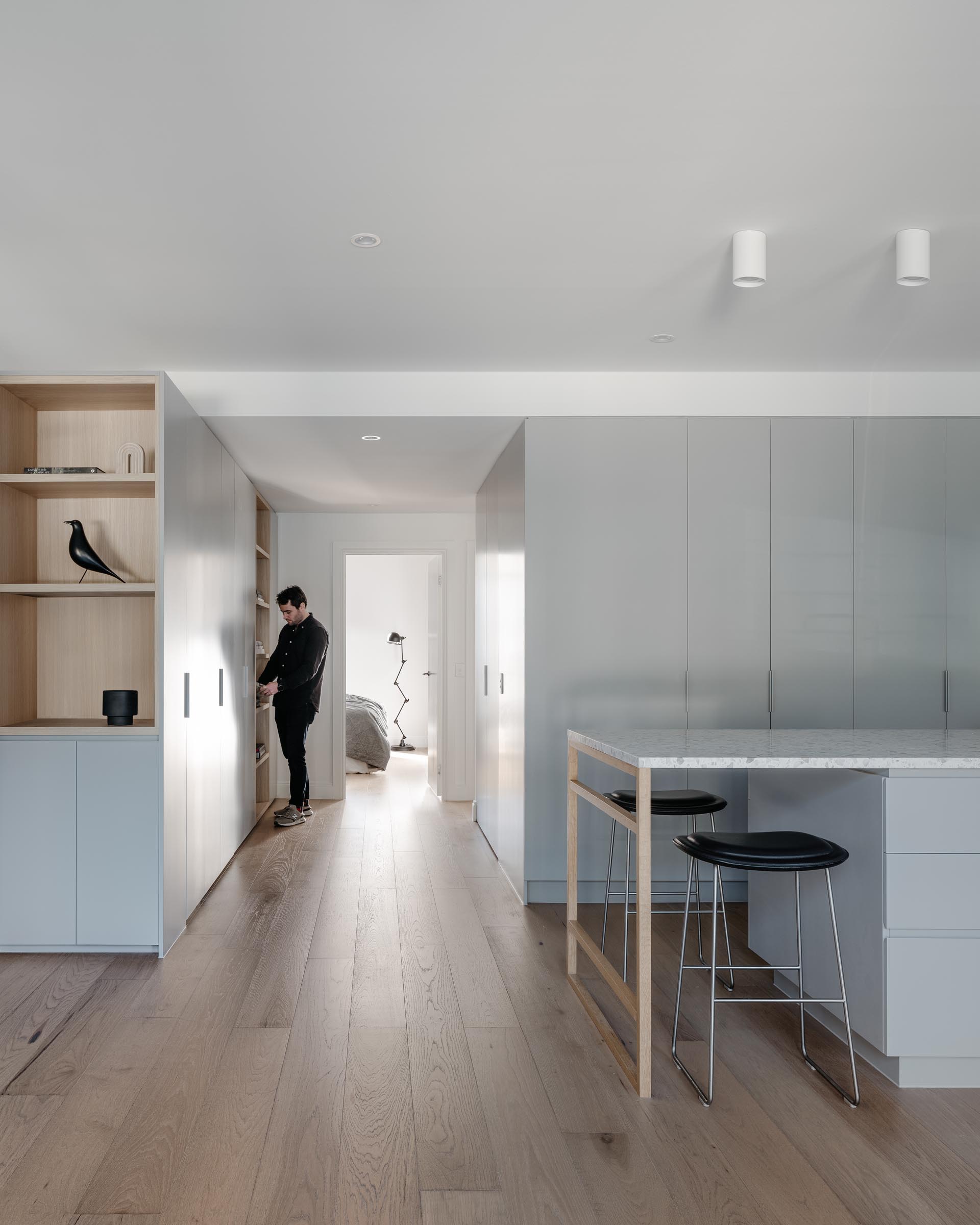Современные апартаменты со светло-серыми шкафами в минималистском стиле и дубовыми полами.