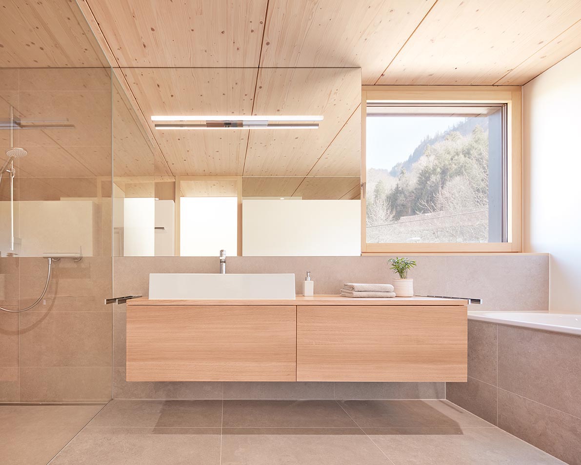 В этой современной ванной комнате квадратное окно создает прекрасный вид на деревья, а парящая деревянная раковина отделяет душ от встроенной ванны.