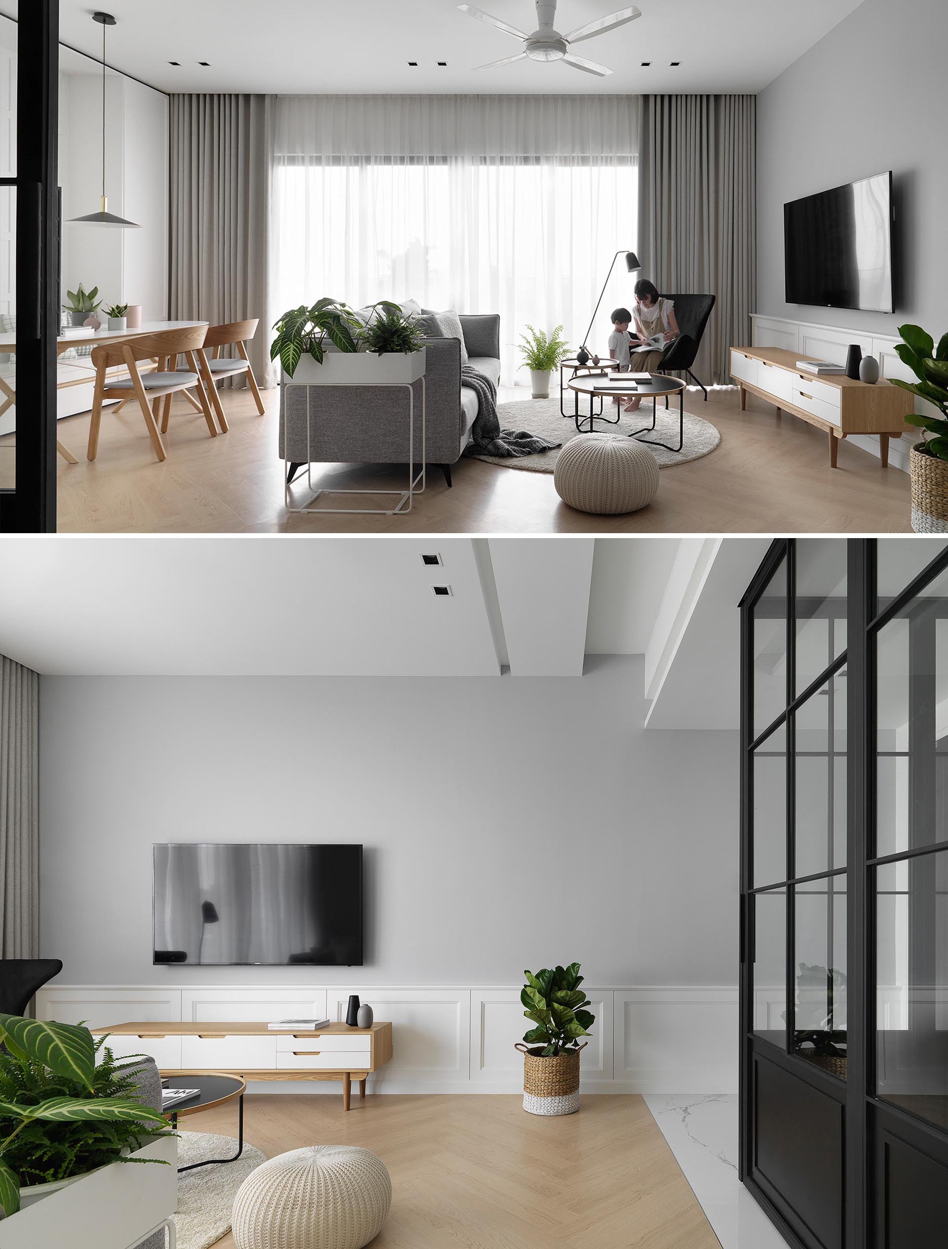 В гостиной современной квартиры серая акцентная стена, шторы от пола до потолка и диван дополняют светлые тона дерева и белые акценты.