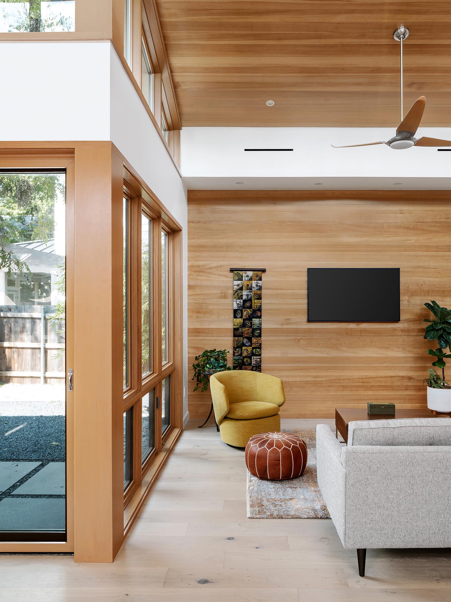 В этой современной гостиной высокий наклонный потолок создает возвышенную и открытую среду, а дерево добавляет пространству ощущение тепла.