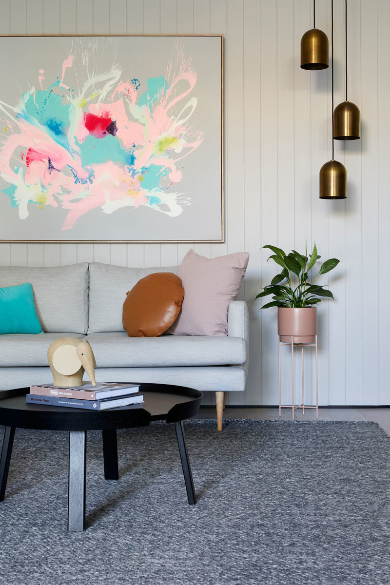 Идеи для гостиной. В этой современной гостиной белые стены размещены над диваном, а над растением на подставке для растений висят три металлических подвесных светильника. #LivingRoomIdeas #LivingRoom #Decor #InteriorDesign