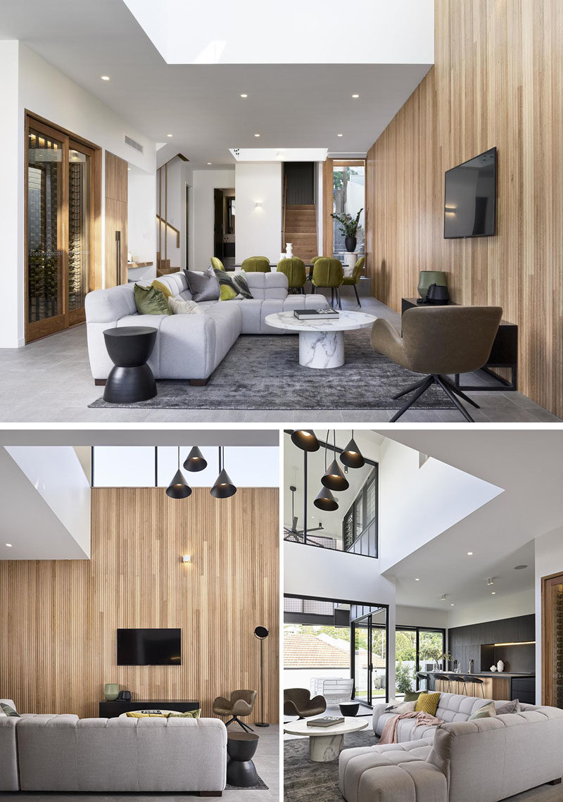 Идеи для гостиной - стена с деревянным акцентом соединяет столовую и гостиную в этом современном доме. Пустота над гостиной заполнена множеством подвесных светильников, а потолочное окно добавляет естественного света в течение дня. #LivingRoomIdeas #ModernLivingRoom #WoodAccentWall