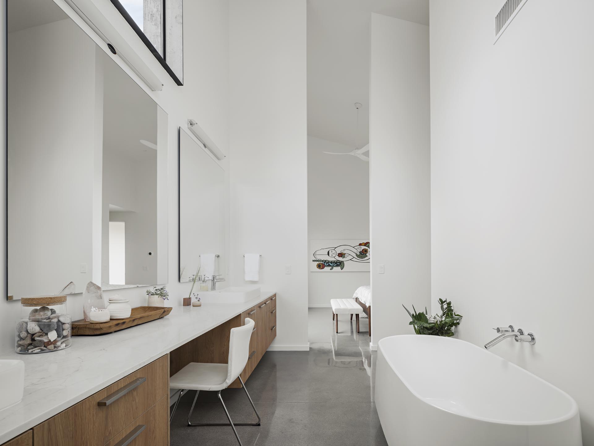 В современной ванной комнате есть длинный туалетный столик и отдельно стоящая ванна.