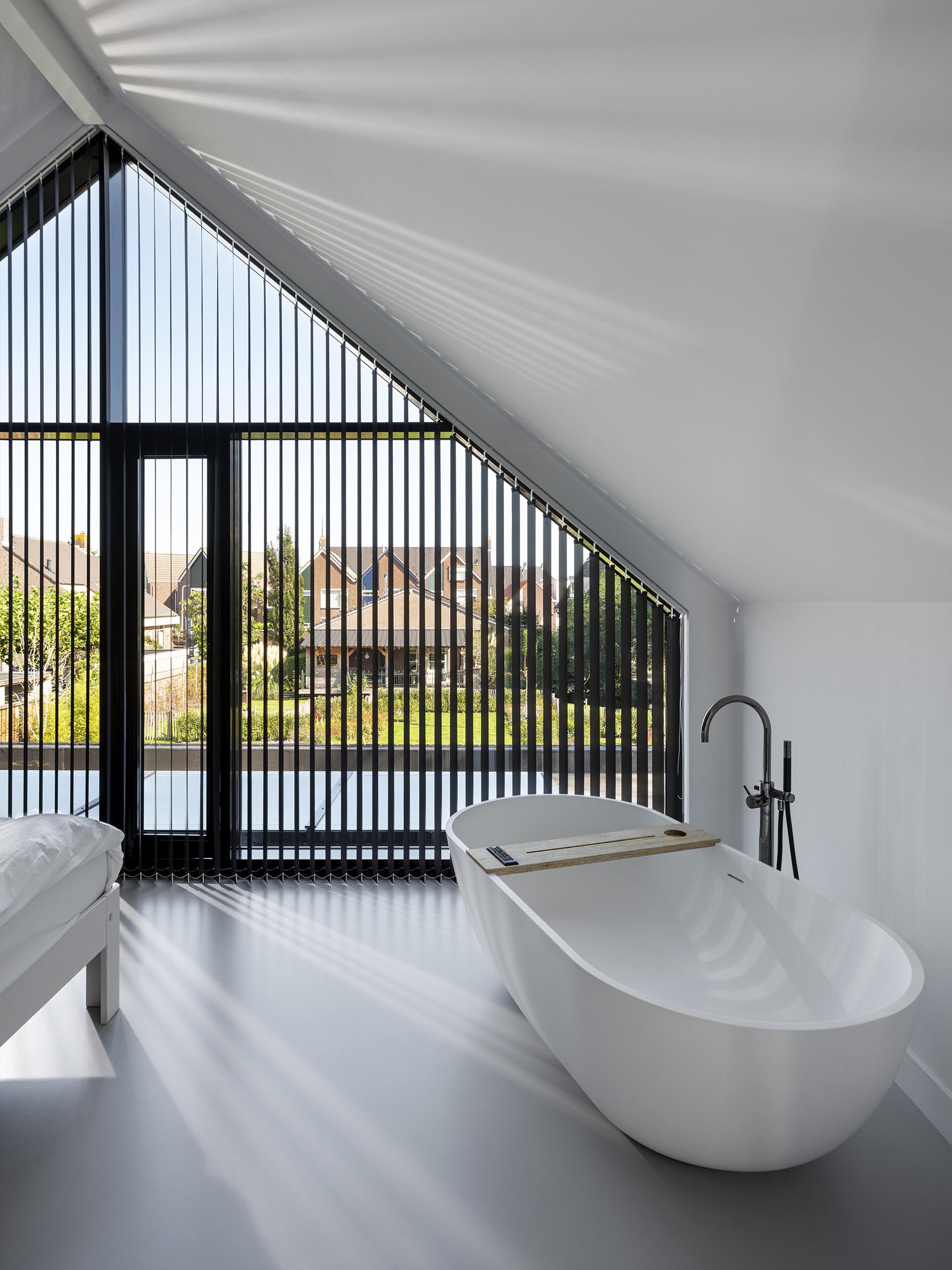 В этой современной главной спальне есть окна, совпадающие с линией крыши, и отдельно стоящая ванна.