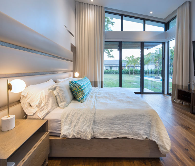 В этой современной главной спальне раздвижные стеклянные двери открываются на задний двор, а кровать нестандартного дизайна включает прикроватные тумбочки и кожаное изголовье. #MasterBedroomIdeas # ModernBedroom #BedroomDesign