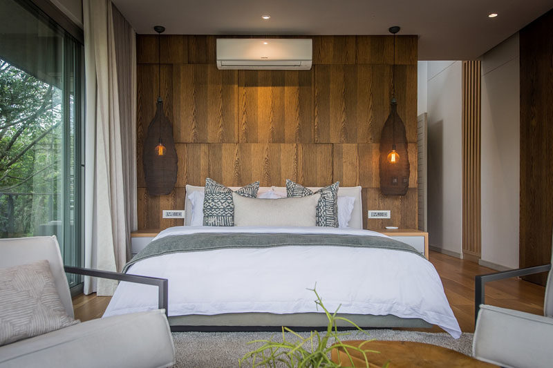 В этой современной спальне отделанная деревянными панелями стена с акцентом на текстуру демонстрирует фактуру, а изящные подвесные светильники в форме корзины располагаются по обеим сторонам кровати. #BedroomDesign #BedroomIdeas #WoodAccentWall