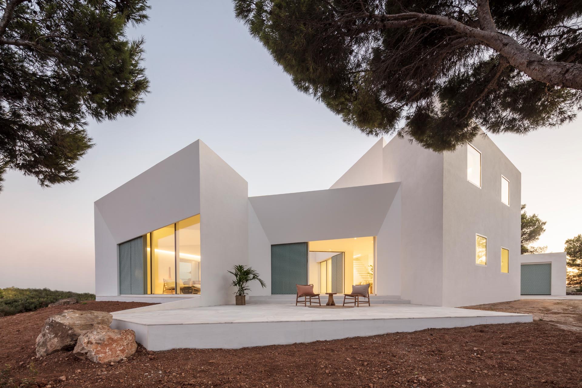 Современный белый дом с перфорированными алюминиевыми экранами пастельно-бирюзового цвета и угловатым дизайном.