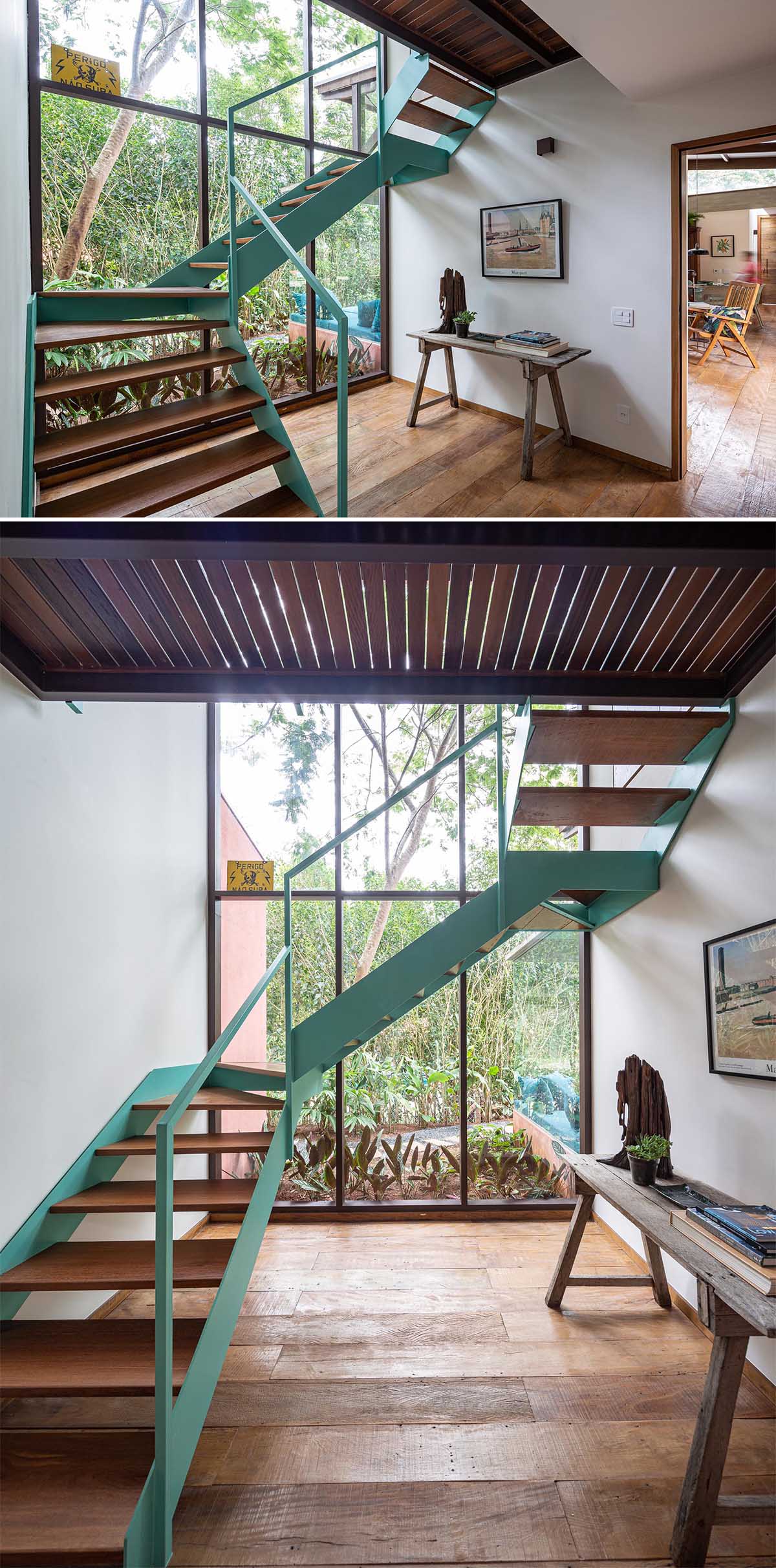 Лестница со светло-бирюзово-синей рамой и деревянными ступенями соединяет два уровня дома.