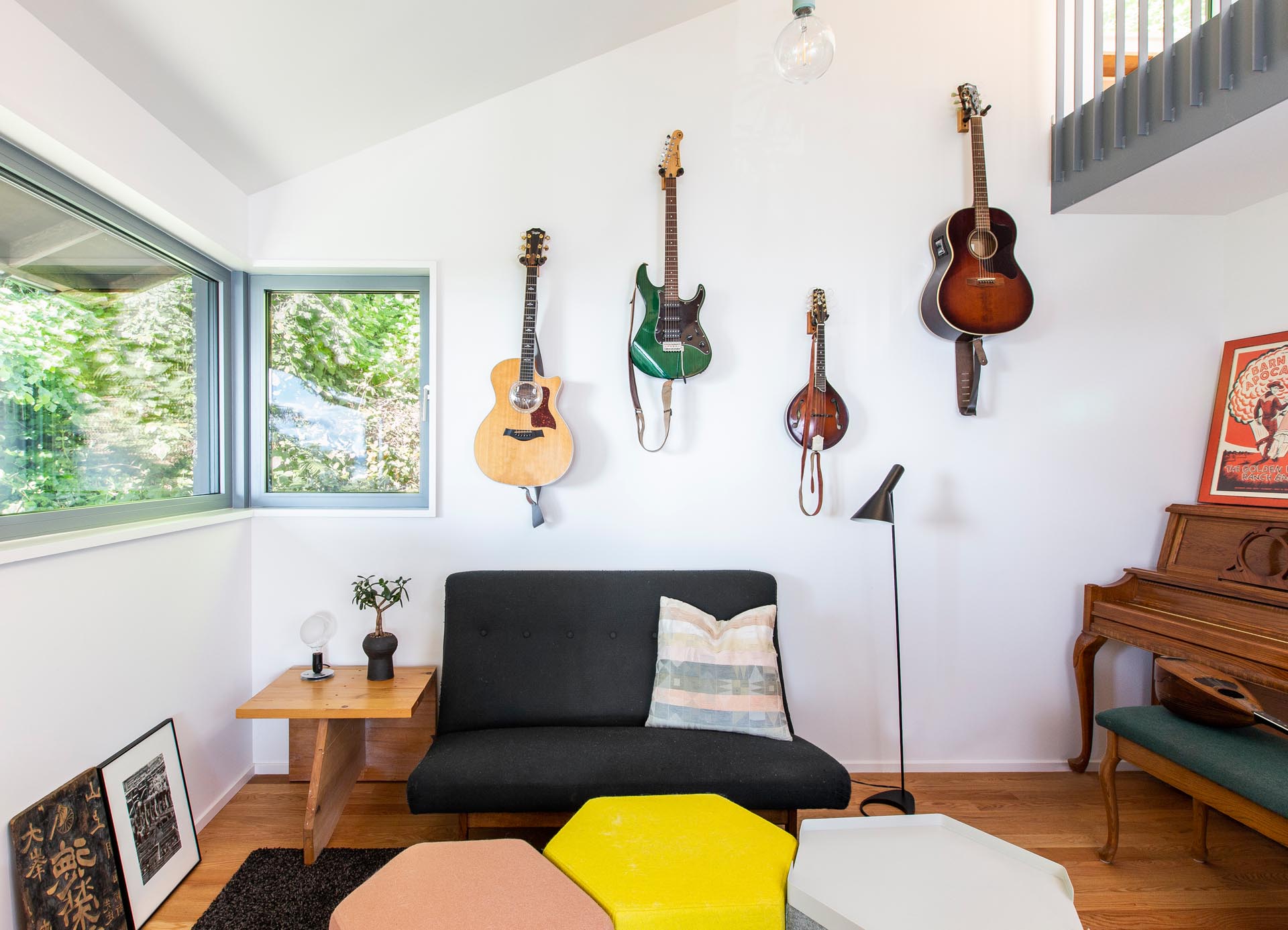 В небольшом уголке гостиной спрятан музыкальный уголок с висячими гитарами, пианино и небольшим диваном.