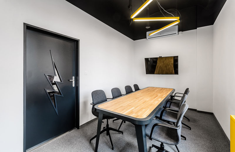 В этом современном офисе элементы, напоминающие молнии, можно найти в зале заседаний с верхним освещением и формой окна в двери.