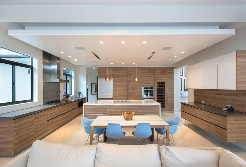 Эта большая современная кухня с деревянными шкафами делит пространство с обеденной зоной. #KitchenDesign #WoodKitchen