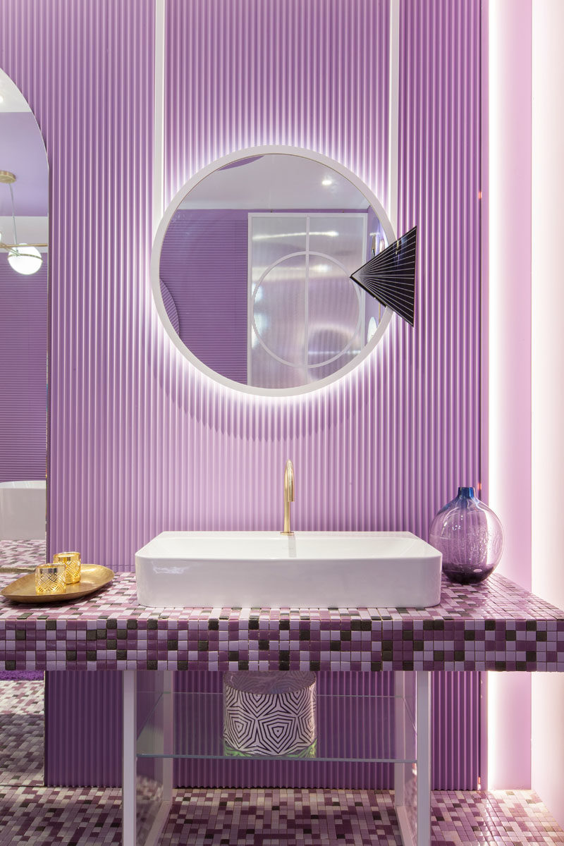 Идеи для ванных комнат - мозаичный туалетный столик в оттенках фиолетового расположен под алюминиевыми зеркалами с подсветкой, которые обеспечивают мягкое свечение и подчеркивают текстурированную стену. # Идеи для ванной # Дизайн ванной # ФиолетовыйВанная # Фиолетовая Плитка