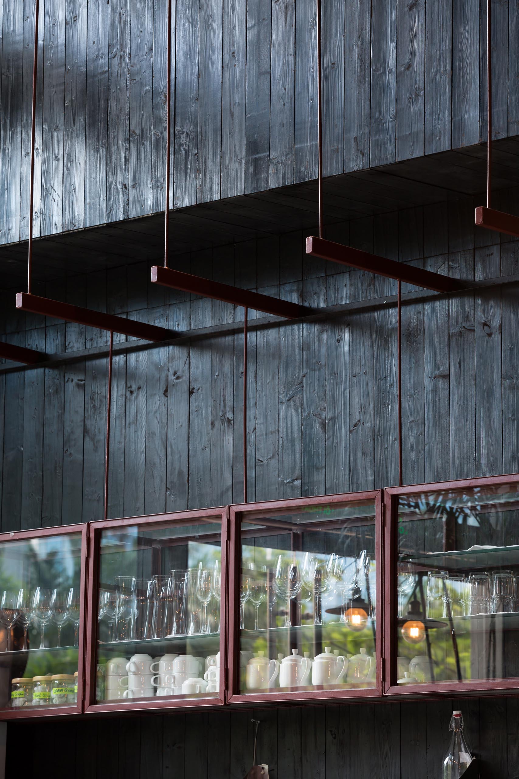 Современный ресторан со стенами из черного дерева и стеклянной витриной.