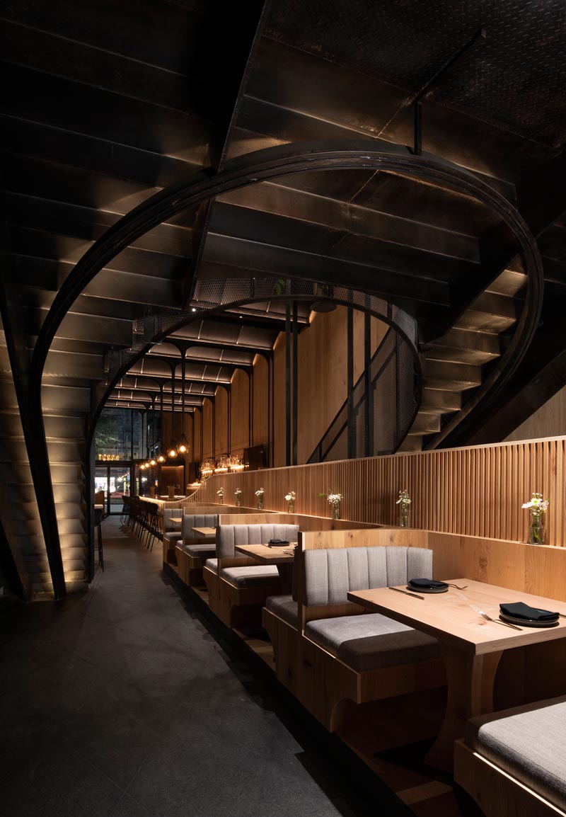 Этот современный ресторан имеет высокий сводчатый потолок, деревянные стены, скрытое освещение, большой бар и различные обеденные зоны, включая кабинки и банкетные столики. #RestaurantInterior #ModernRestaurant #BarInterior #BarDesign