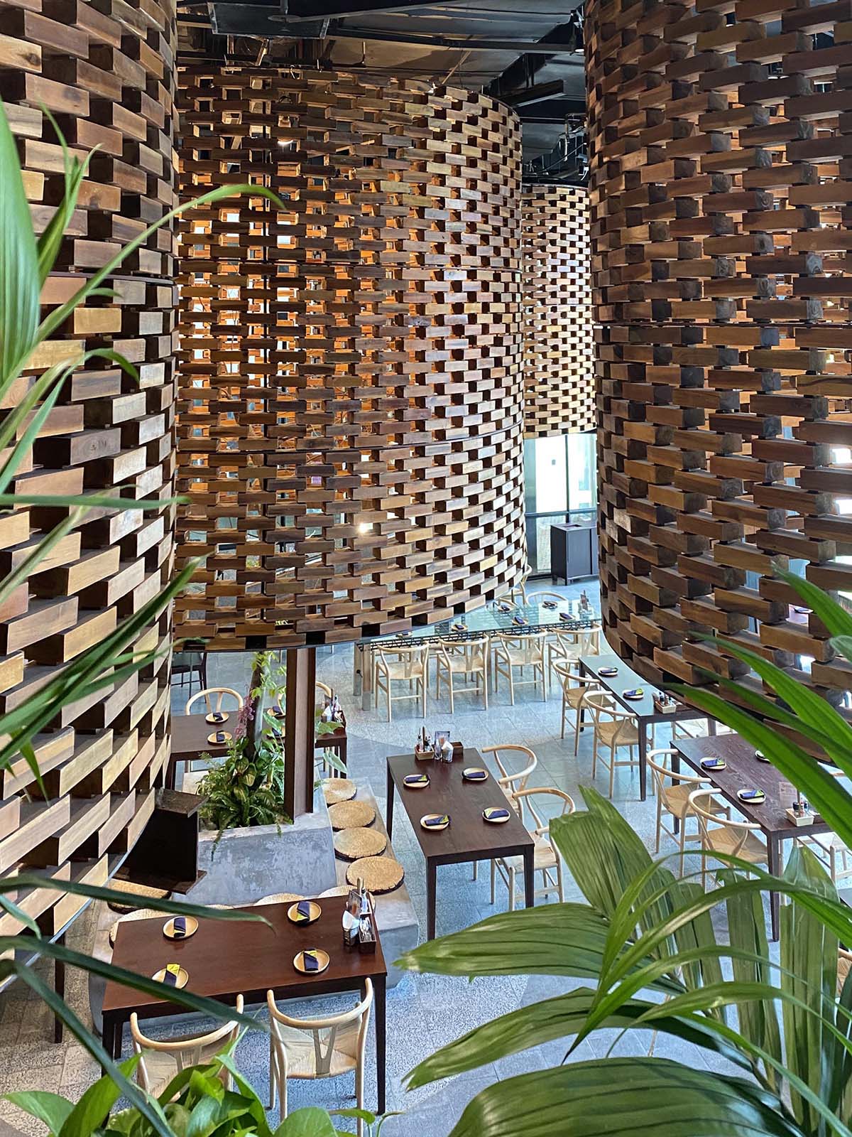 Современный интерьер ресторана с большими скульптурными цилиндрами из деревянных кирпичей и современной деревянной мебелью.