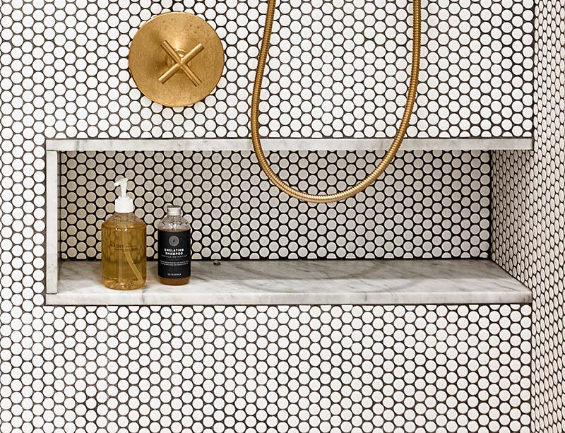Душевая ниша, облицованная тем же мрамором, что и туалетный столик, была добавлена ​​в душ, чтобы обеспечить место для хранения бутылочек с шампунем и мыла. Это позволяет просвечивать дизайн душа, поскольку нет дополнительных полок, прикрепленных к стене или свисающих с душевых принадлежностей. #ShowerNiche # PennyTiles # BrassFixtures #MarbleAccent # ModernBathroom