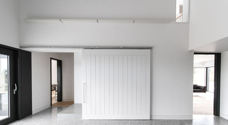 Белая раздвижная дверь сарая в этом современном доме помогает сохранить пространство ярким и уютным и гармонирует с белыми стенами вокруг него.