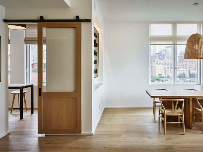 Эта раздвижная дверь сарая отделяет кухню и столовую от гостиной и дополняет остальной интерьер благодаря теплому тону дерева.