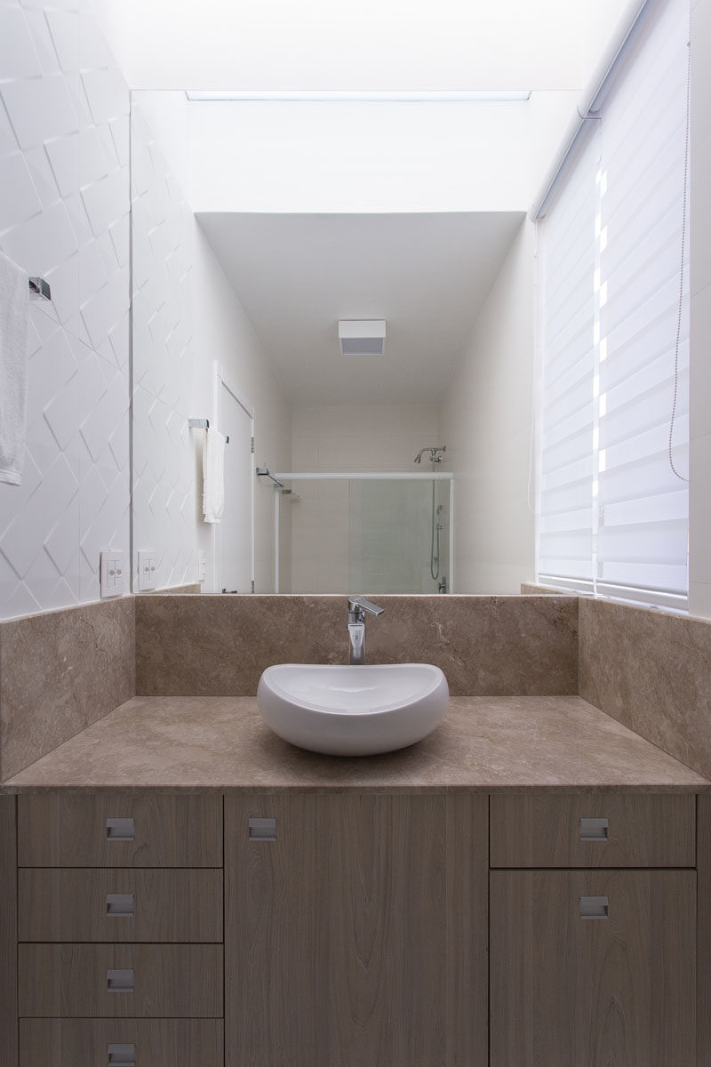  В этой современной ванной комнате комната декоративная белая плитка в ванной комнате, а большое зеркало помогает сделать маленькое пространство больше, чем оно есть на самом деле 