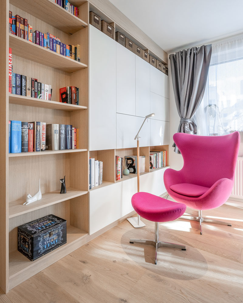 Идеи для библиотеки - в этих современных апартаментах есть небольшая библиотека с книжными полками и ярко-розовым креслом. #HomeLibrary #ReadingCorner #LibraryIdeas #ShelvingIdeas