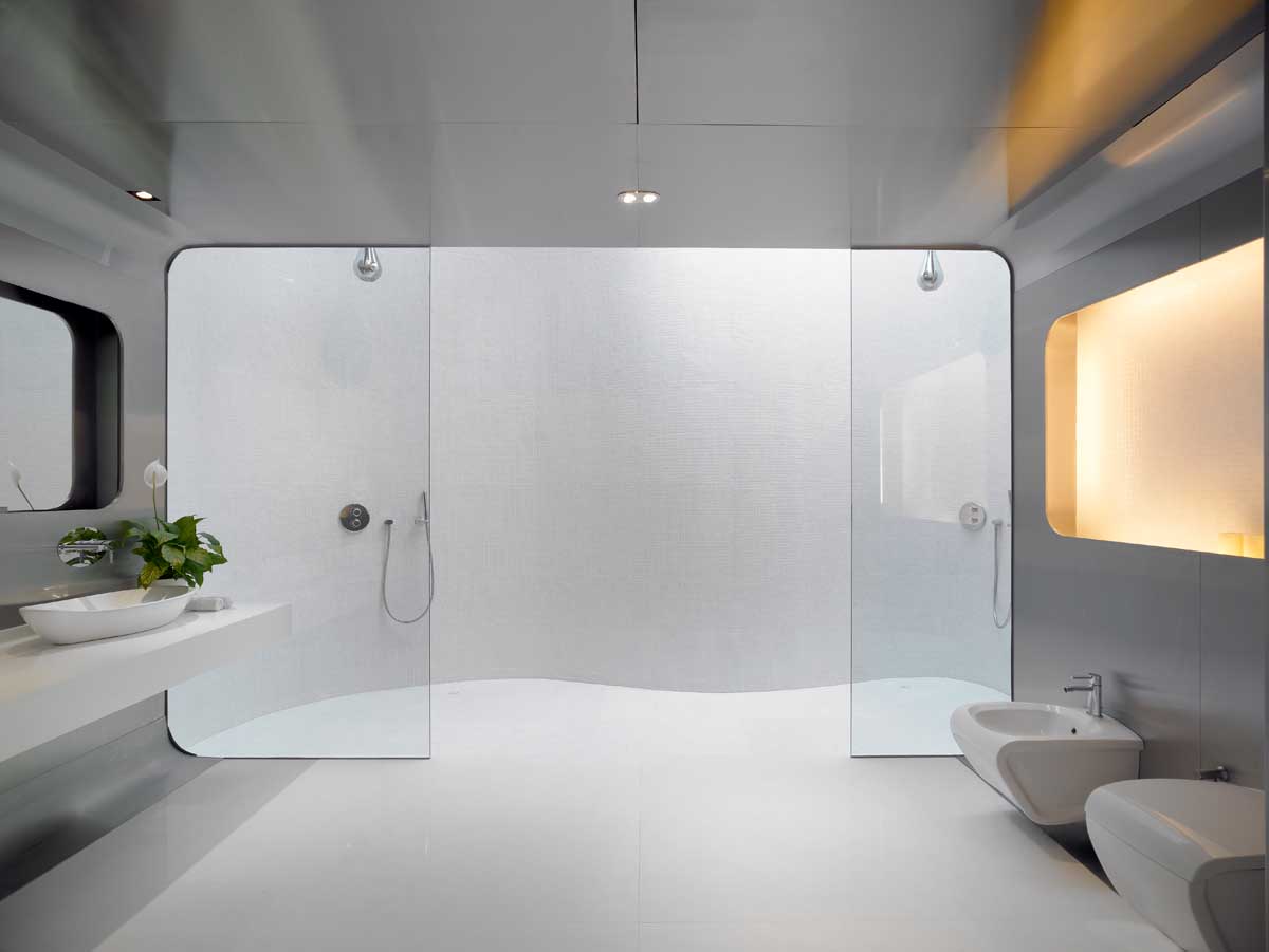 Современная ванная комната со стенами из нержавеющей стали, стеклянными перегородками для душа и двойным душем с потолочным окном.