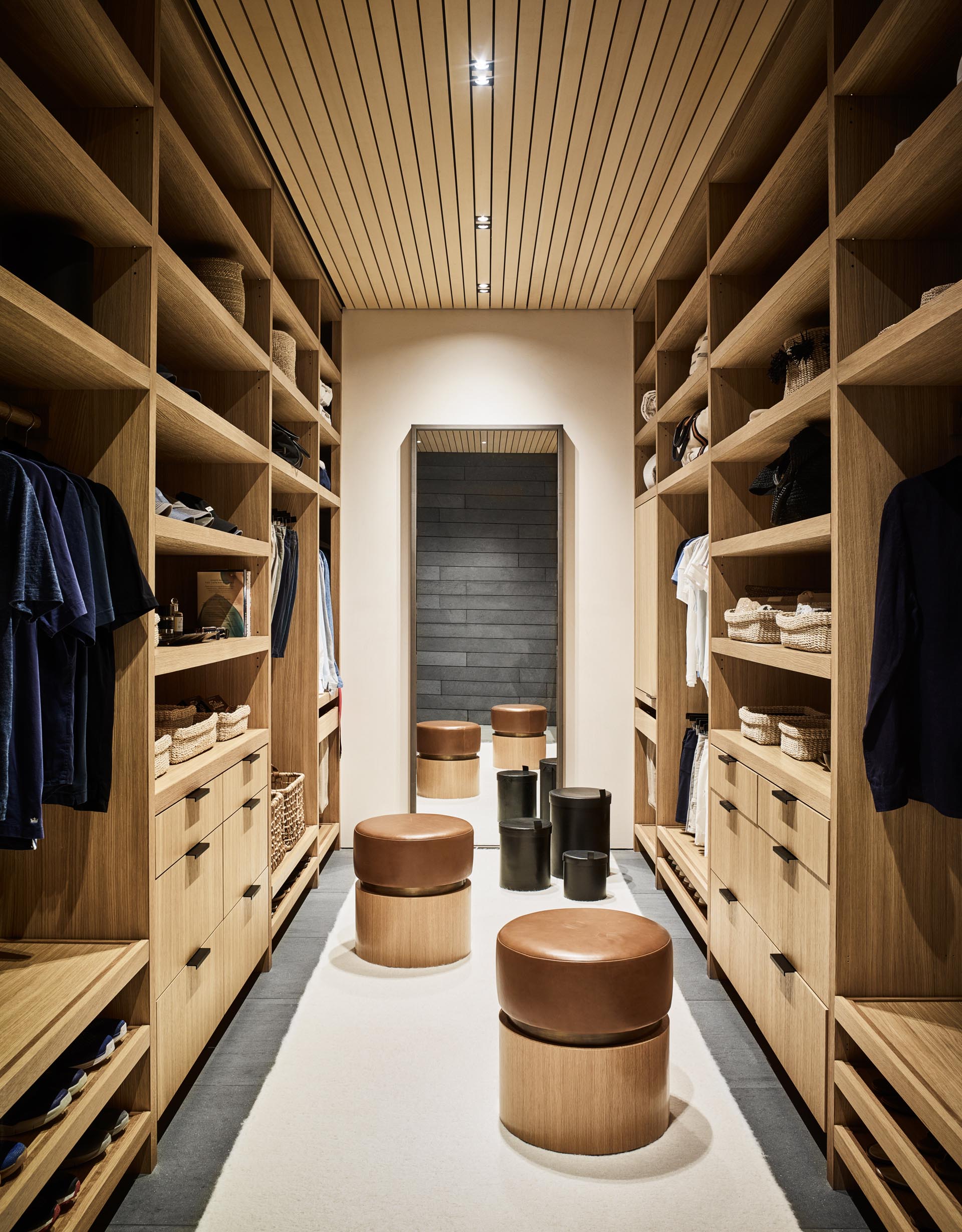Современная гардеробная с полками от пола до потолка, ящиками и местом для развешивания одежды.