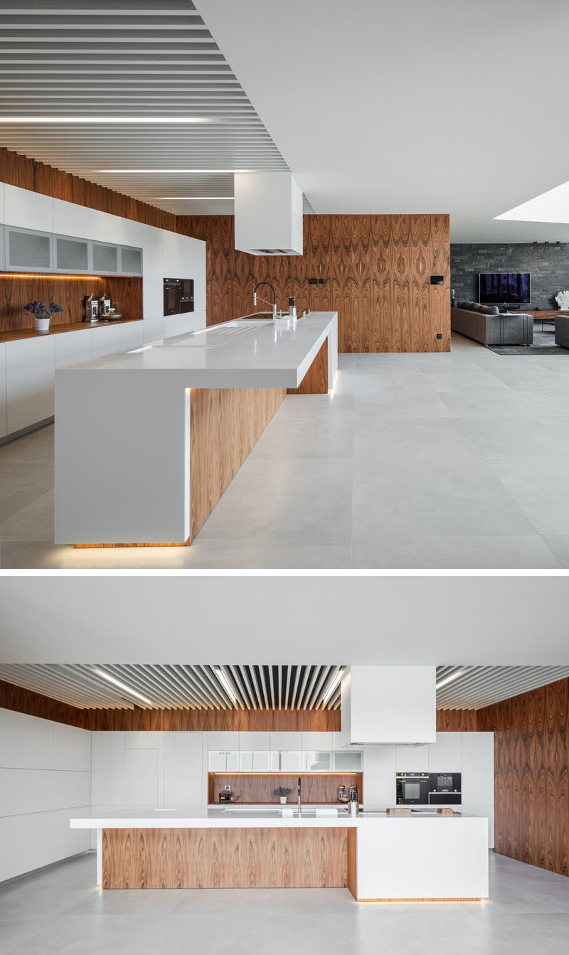  Интерьер этого современного дома позволяет легко перемещаться между различными социальными зонами дома. Кухня состоит из деревянных стен, которые используются для белых шкафов. #ModernKitchen #WoodAndWhiteKitchen #KitchenDesign 