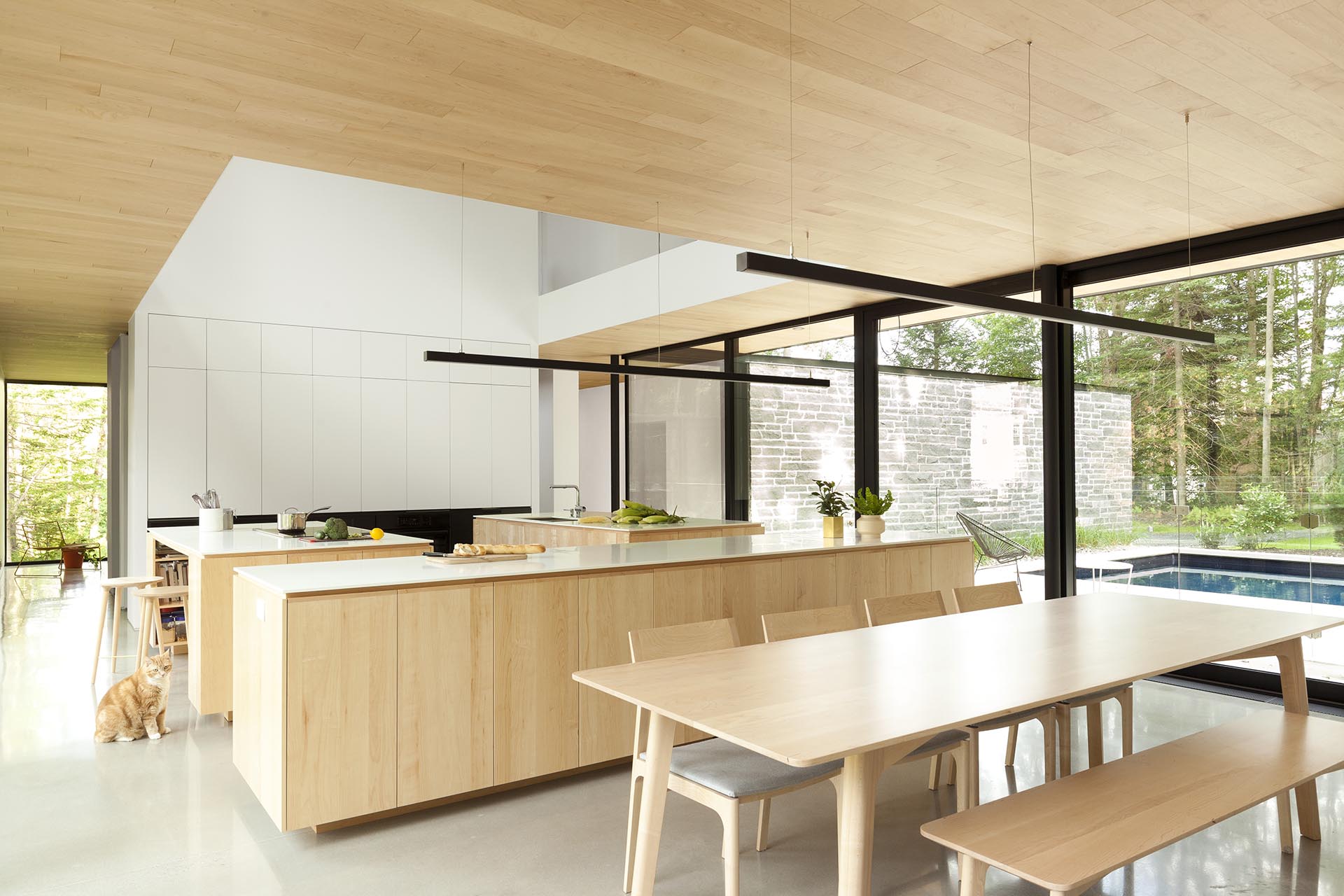 Современная кухня с тремя кухонными островками с основанием из светлого дерева и белыми столешницами.