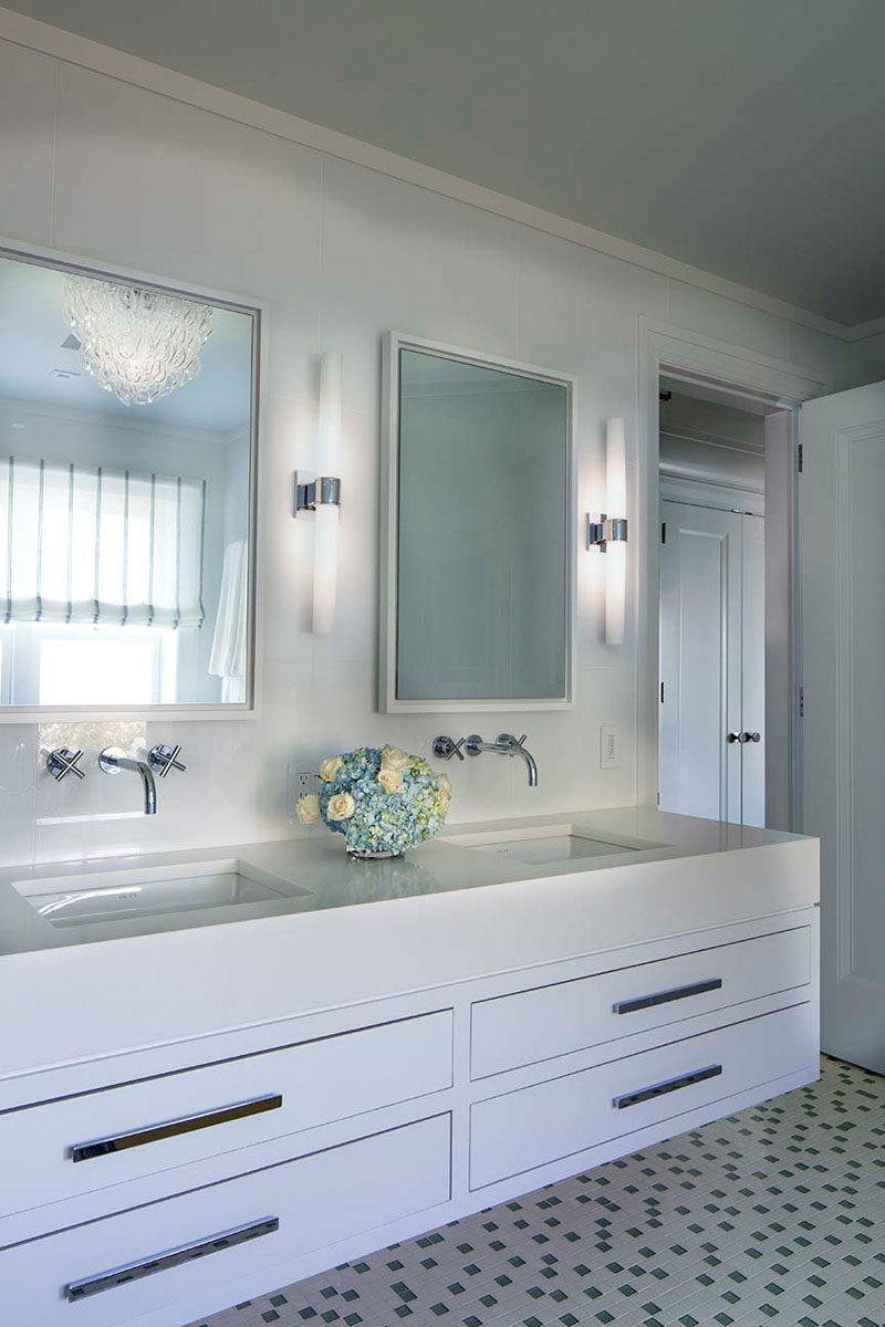 Идеи для ванных комнат - в этой современной ванной комнате под двойными зеркалами стоит плавающий белый туалетный столик, а пол покрыт небольшой квадратной плиткой с темными вставками. #BathroomIdeas # ModernBathroom #BathroomDesign