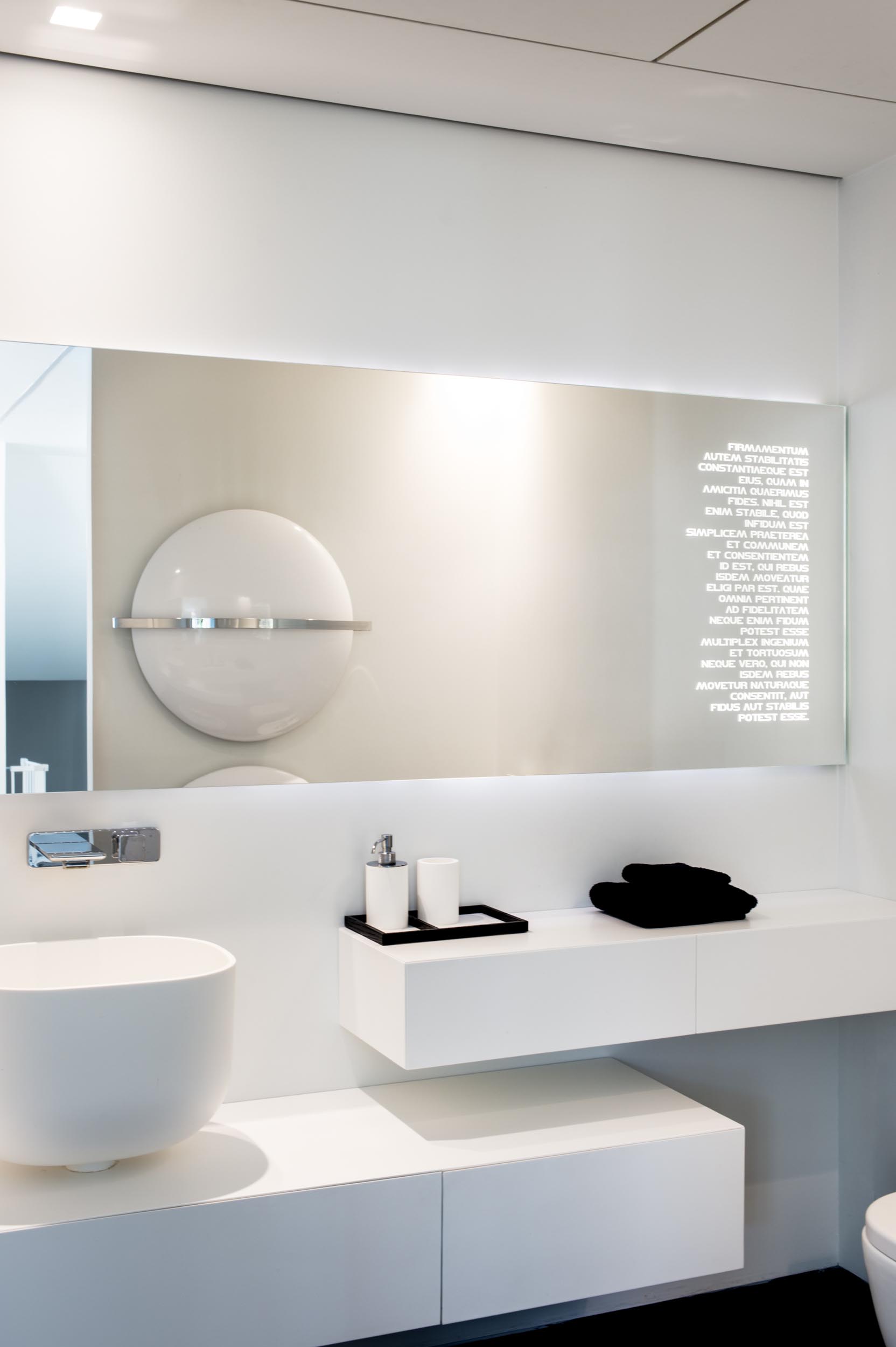 Современная белая ванная комната с белым туалетным столиком и зеркалом с подсветкой.