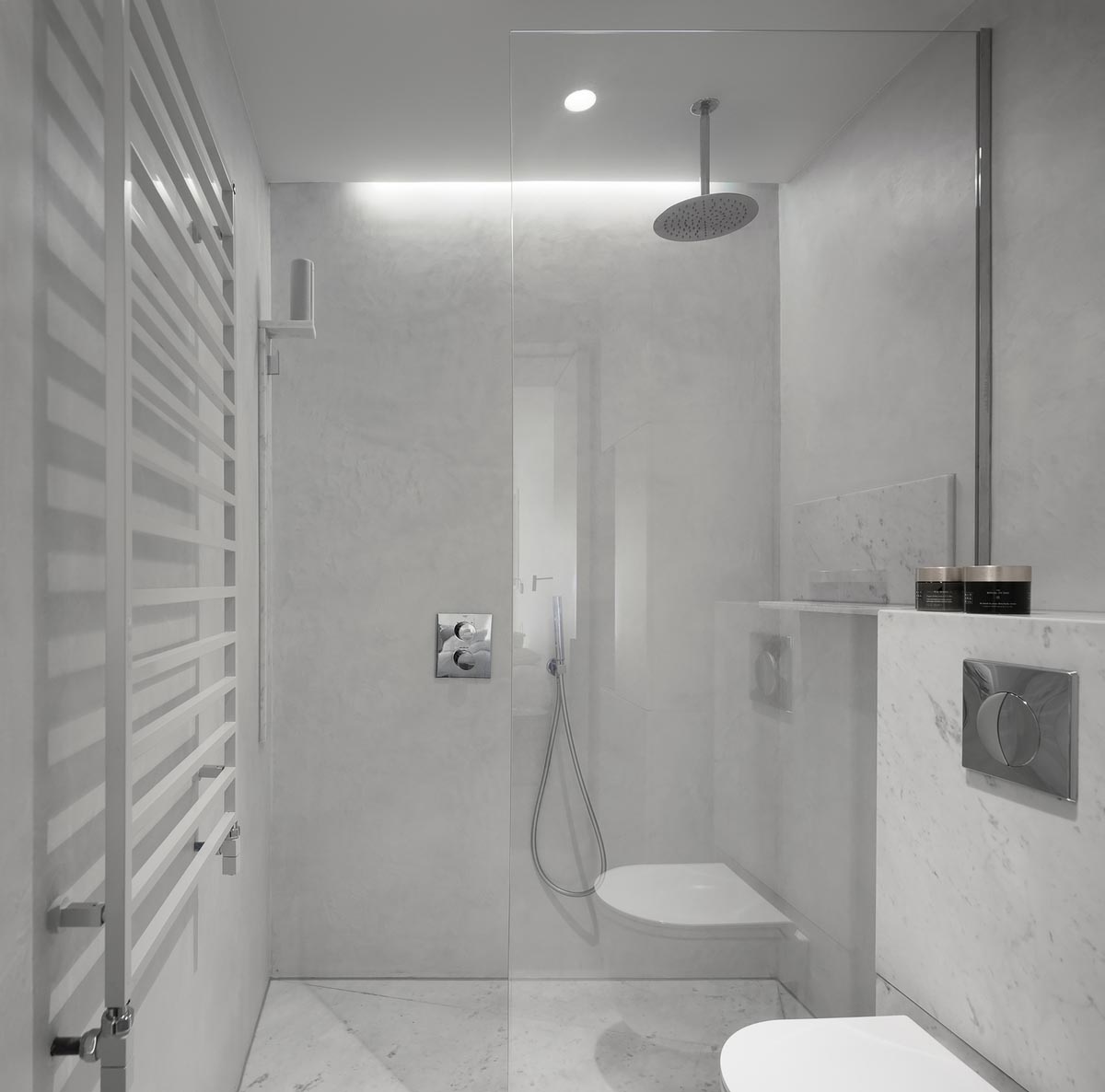 Эта белая главная ванная комната сочетает в себе каррарский мрамор и функциональный бетон, создавая современный вид.
