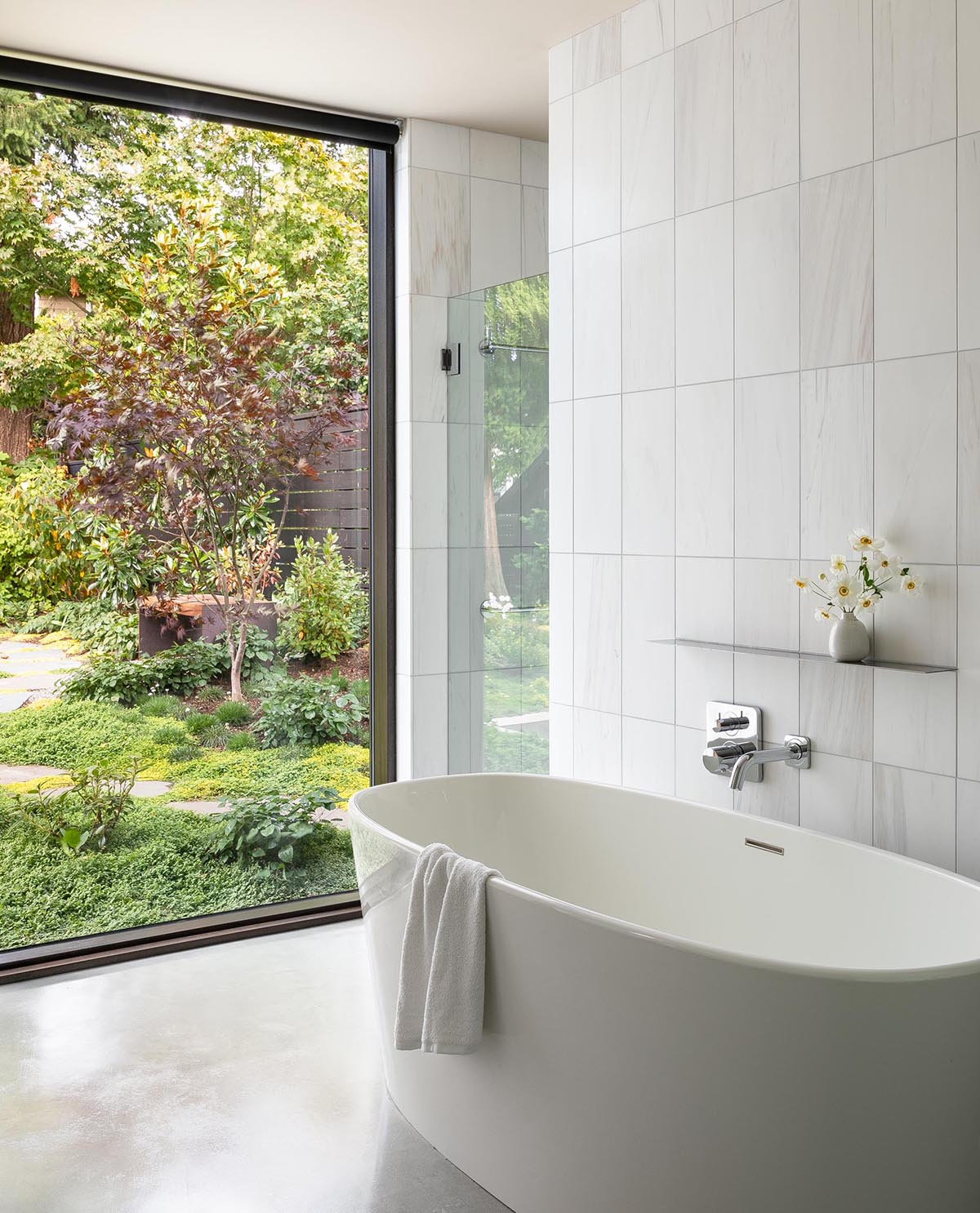 В этой современной главной ванной комнате белая плитка служит фоном для отдельно стоящей ванны и душевой кабины.