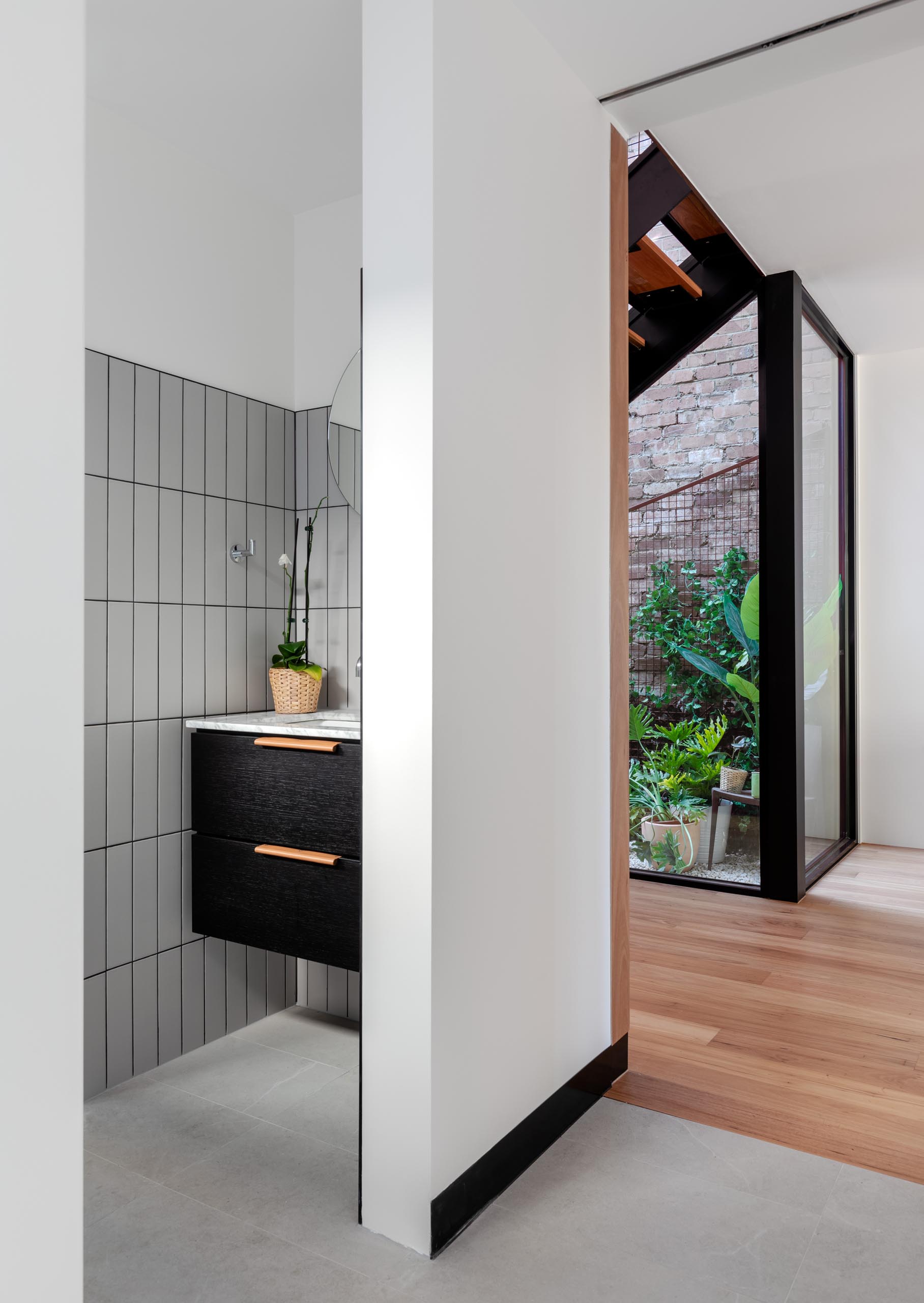Современная ванная комната со светло-серой прямоугольной плиткой и черной раковиной.