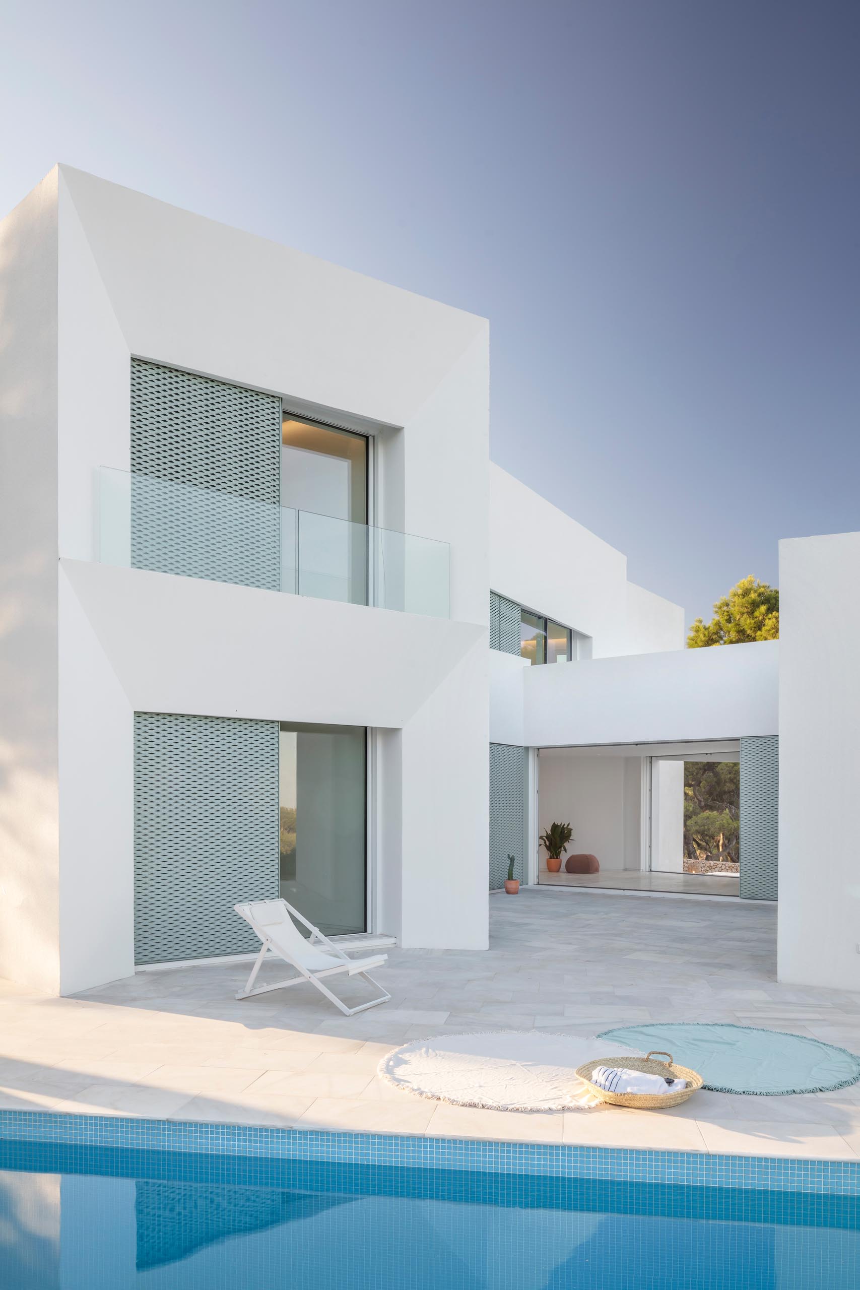 Современный белый дом с перфорированными алюминиевыми перегородками пастельно-бирюзового цвета, патио и бассейном.