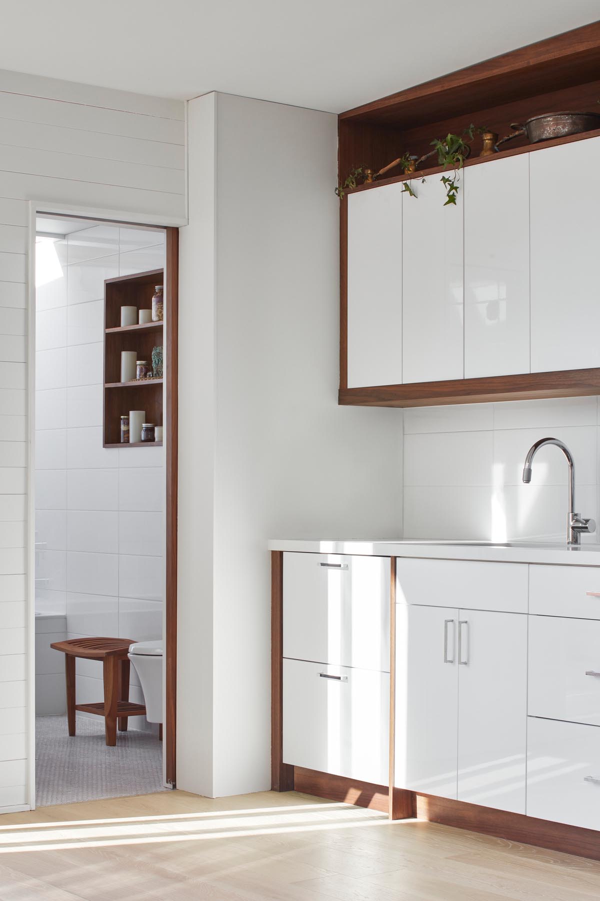 Небольшая мини-кухня с белой и деревянной мебелью и соответствующей белой столешницей.