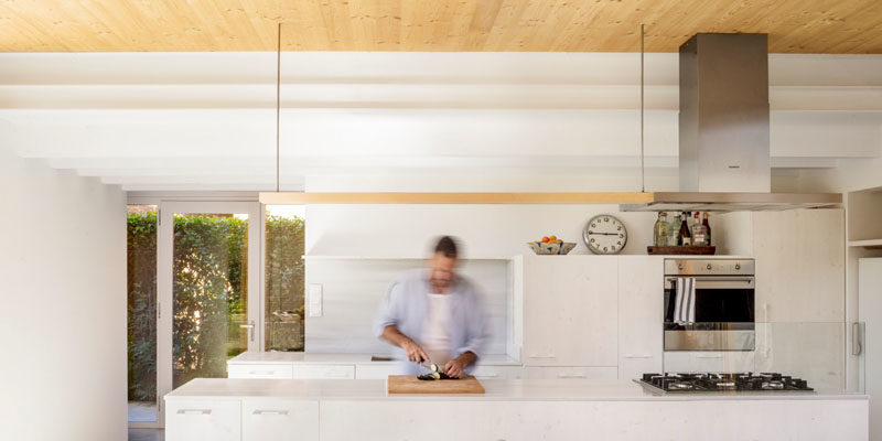 Деревянный потолок в этом современном доме добавляет естественности полностью белой кухне. #KitchenDesign #WhiteKitchen