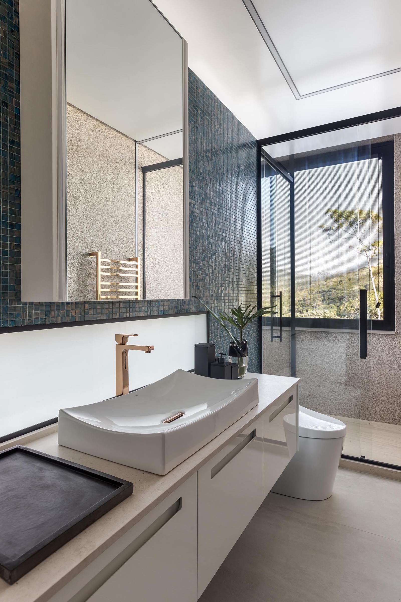 Акцентная стена, выложенная синей плиткой, служит фоном для белого туалетного столика и зеркала в этой современной ванной комнате.