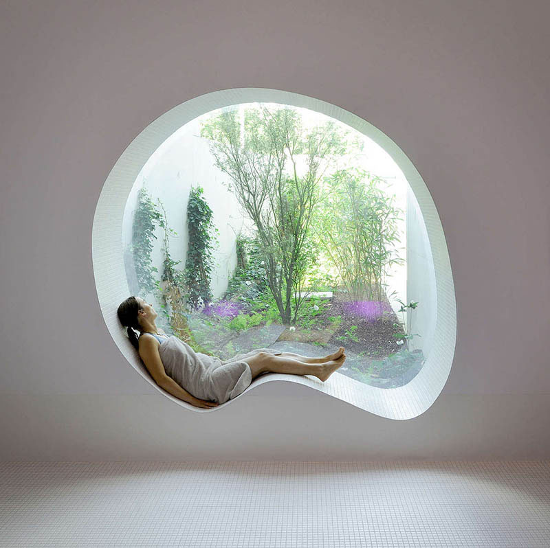  Это современное белое изогнутое сиденье у окна идеально подходит для мечтаний и выходит окнами на тихий сад 