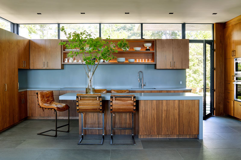 Эта современная кухня имеет мягкие синие столешницы и фартук, деревянную мебель и открытые стеллажи с освещением. # Синие столешницы # Деревянные шкафы # Дизайн кухни # Современная кухня