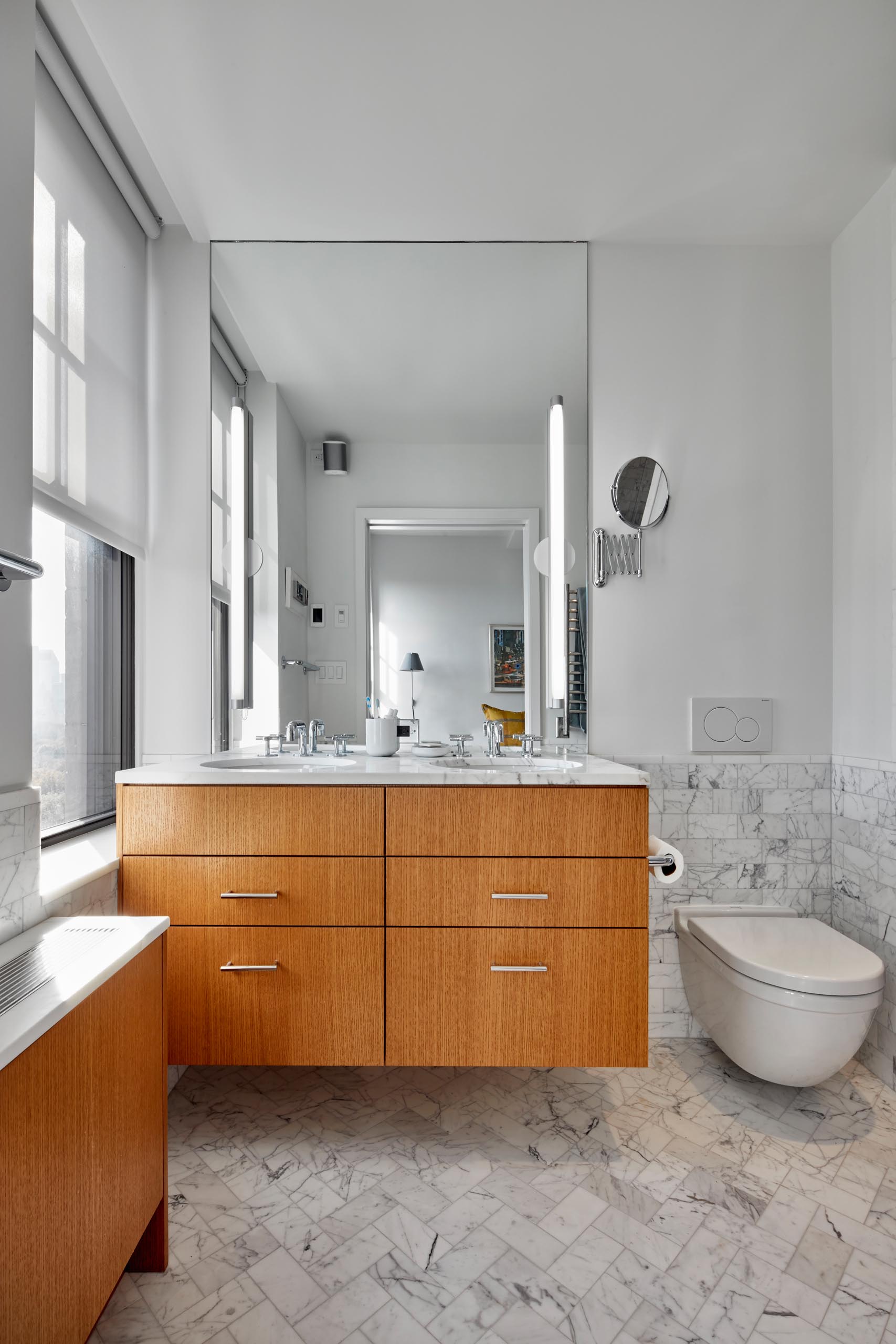 Современная ванная комната с деревянным умывальником, крышкой радиатора и мраморной плиткой.