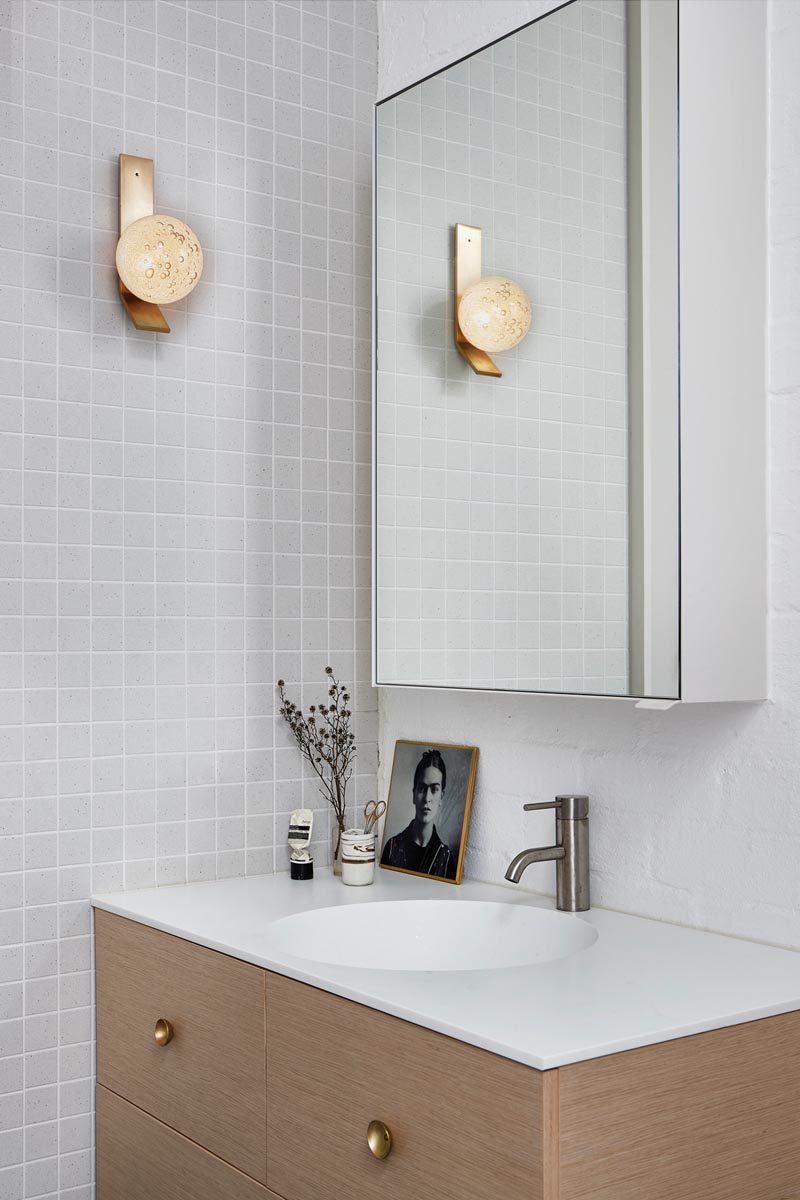 В этой современной ванной комнате простая серая квадратная плитка покрывает стены, а деревянный туалетный столик увенчан белой столешницей, плавно переходящей в раковину. # СовременныеВанная # Светло-серыйВанная