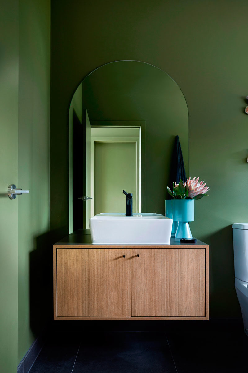 В этой современной ванной комнате парящий деревянный туалетный столик находится под арочным зеркалом, а ваза добавляет яркий синий оттенок. # ВаннаяДизайн # Современный