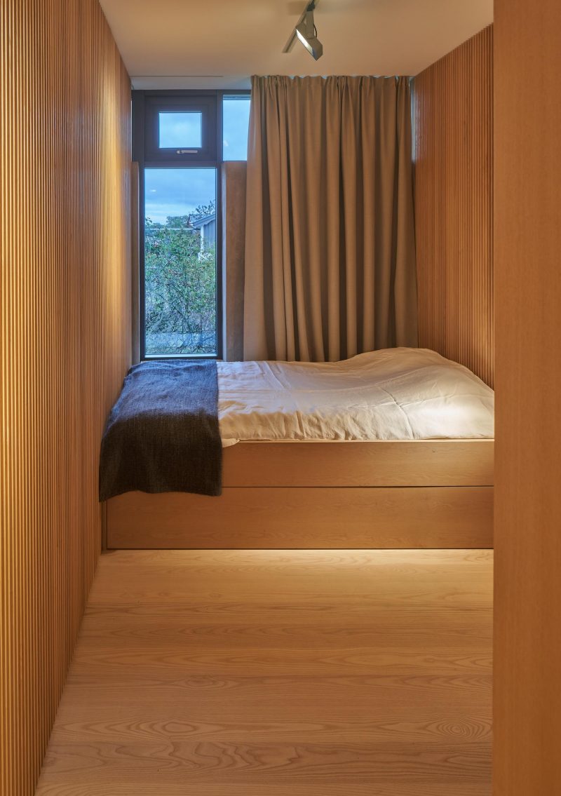 Современная спальня, отделанная деревом, со встроенной кроватью.